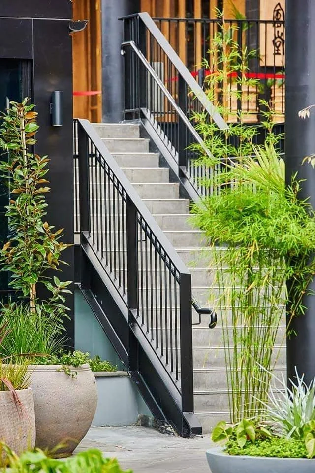 commercial handrail leading up outdoor steps surrounded by greenery