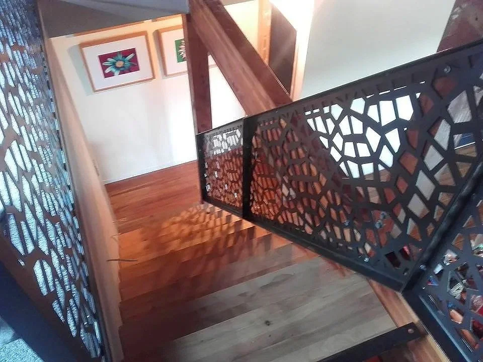 View of a staircase with a decorative black railing and wooden stairs.