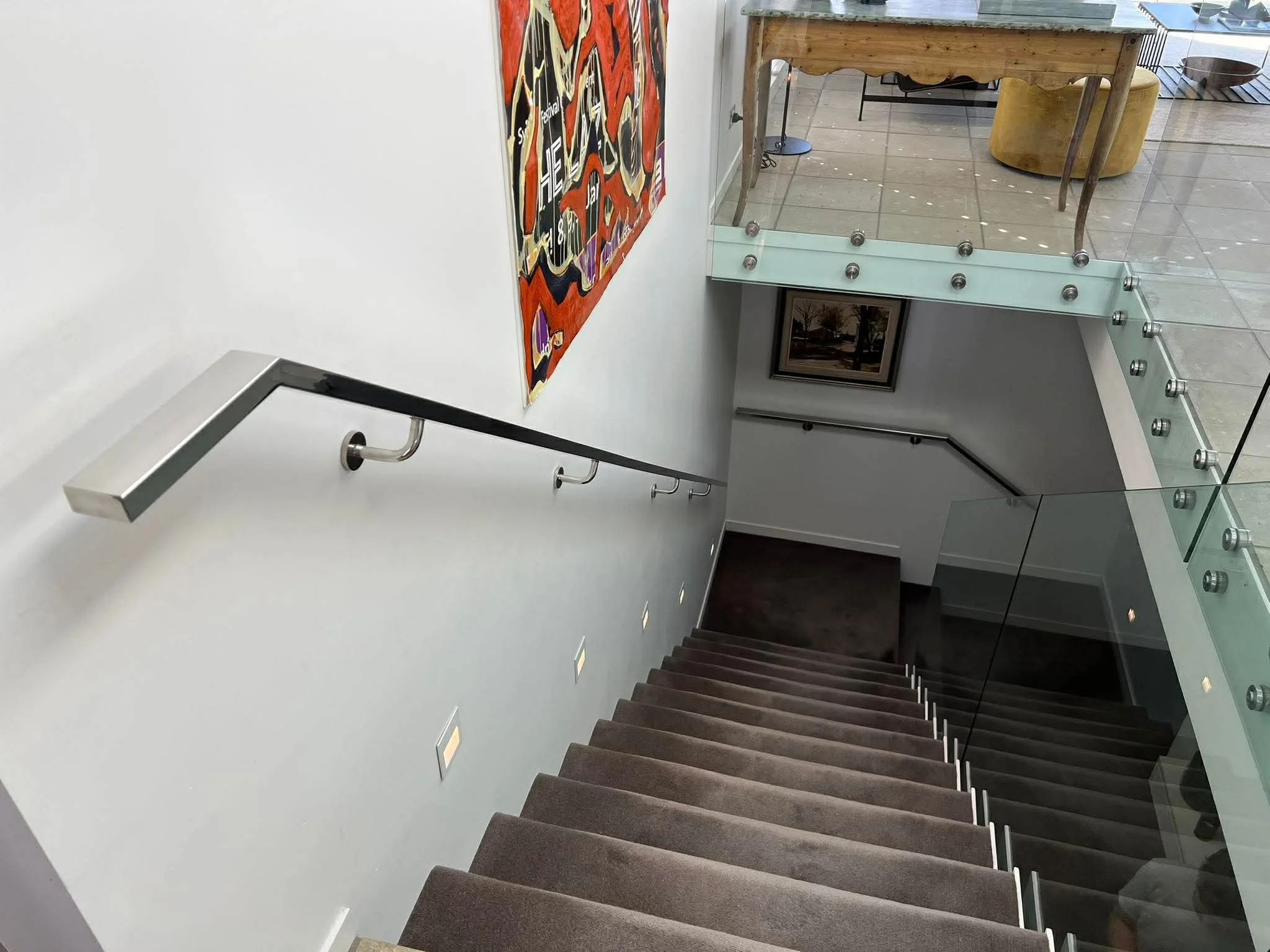 stainless steel interior handrail leading down some carpeted stairs - Takapuna