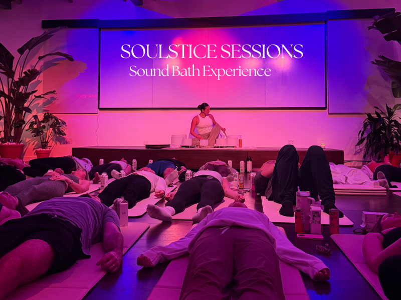 Woman meditating with colorful crystal singing bowls in a serene room.