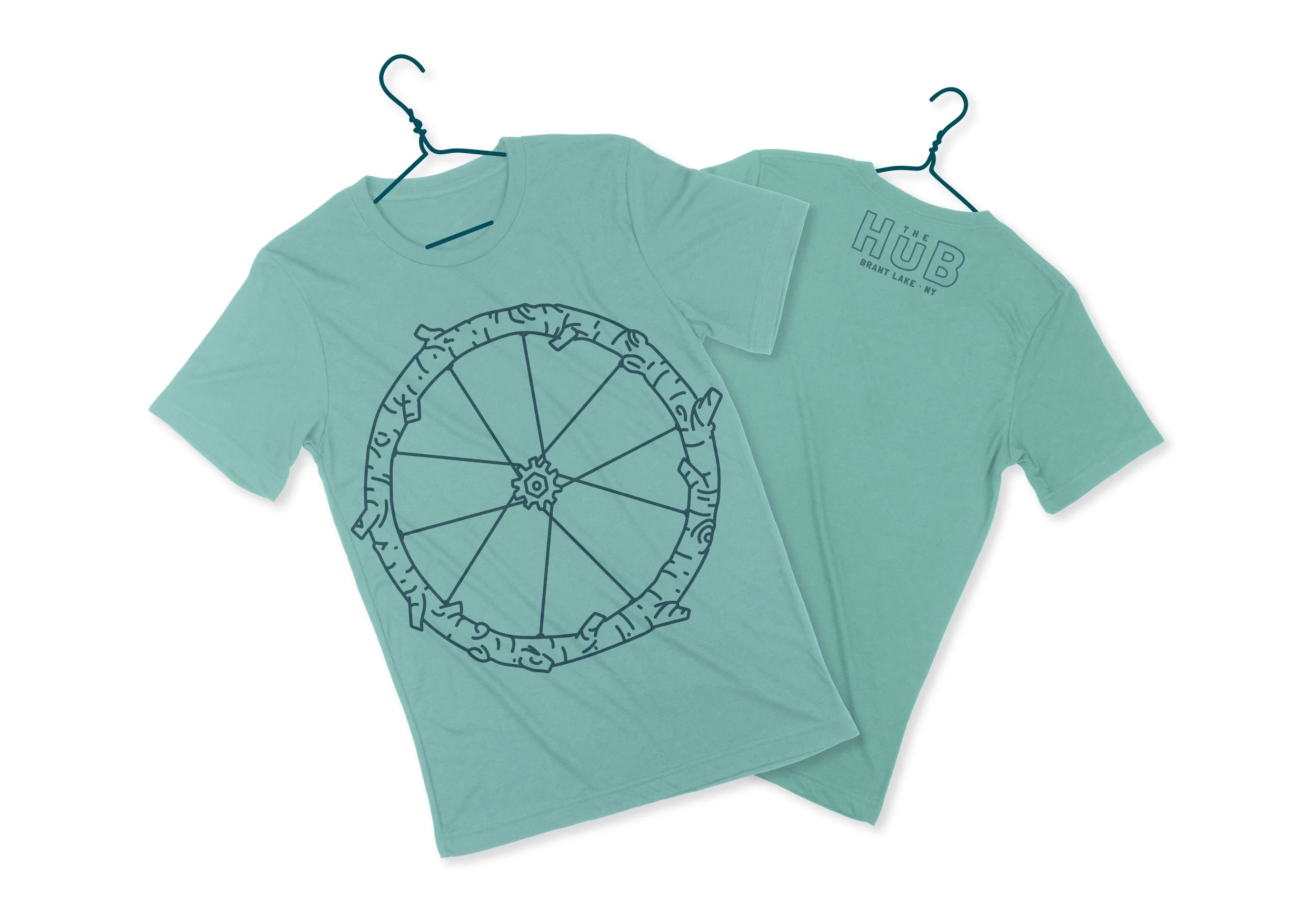 Turquoise t-shirt front and back flatlay with navy blue bike wheel; tire is a tree branch; back text of The Hub Brant Lake NY updated branding