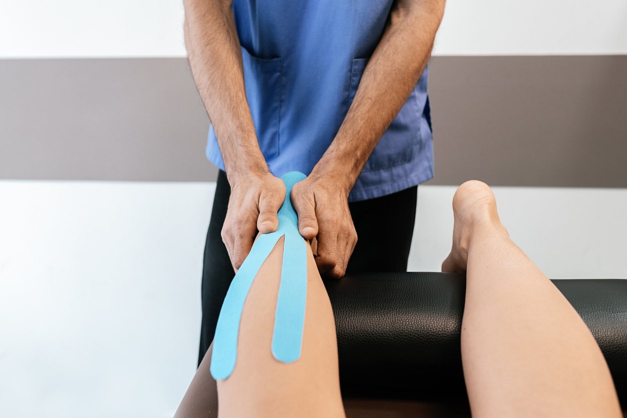 therapist applying KinesioTaping to client's leg