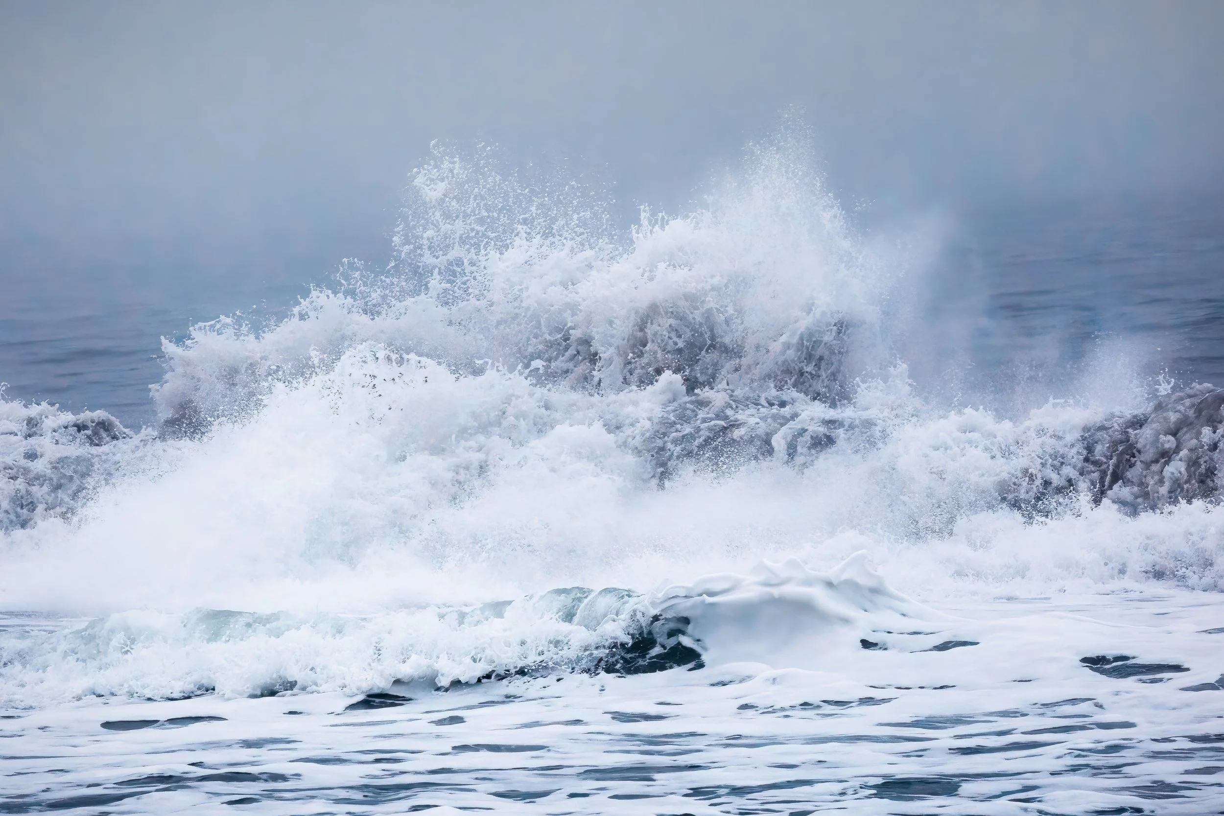 Ocean waves crashing and splashing near the shoreline with foam and spray.