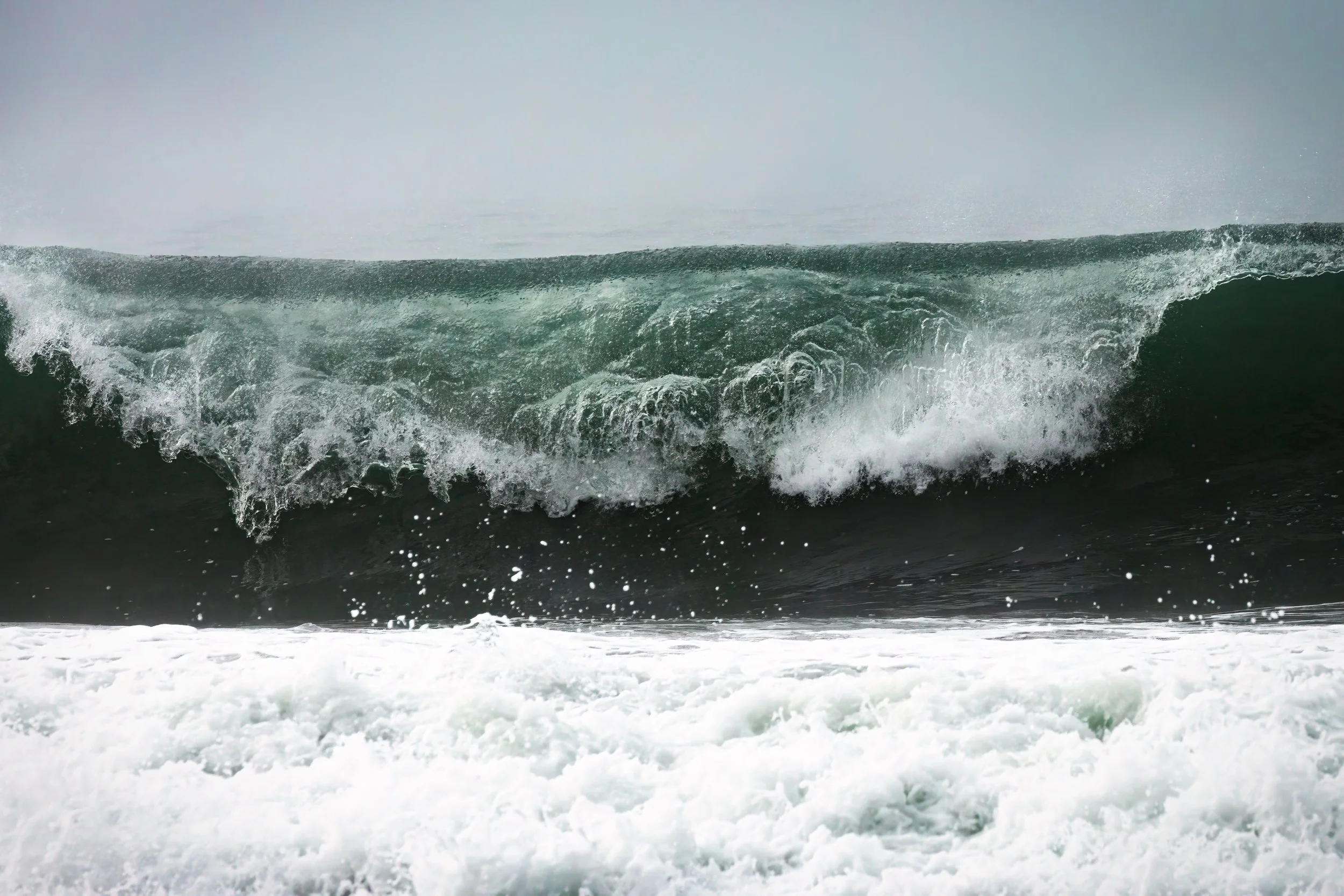 Ocean wave crashing with white foam at the shoreline.