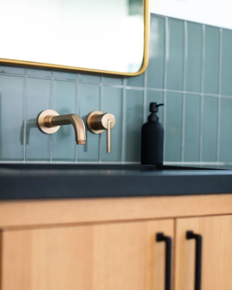 Mixing metals is all about balance, not matching.
 In this bathroom, we layered black and brass to create contrast that feels intentional and elevated. The black countertop and hardware ground the space, while the brass mirror and faucet add warmth a