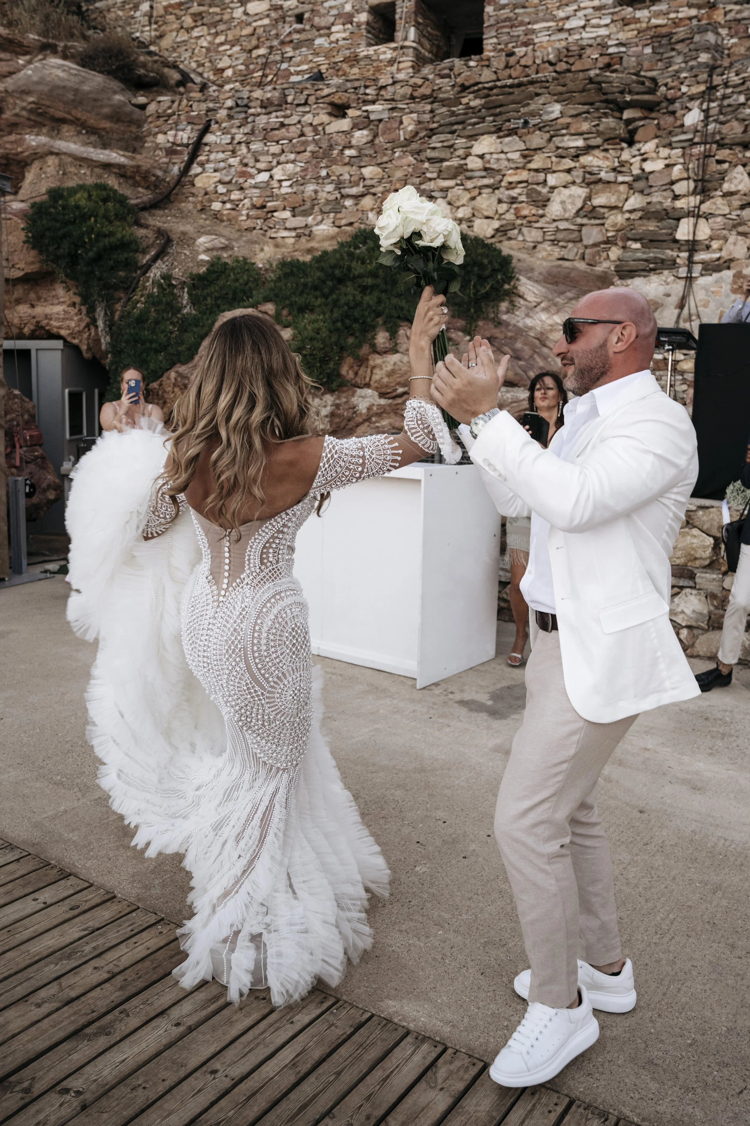 Bride and groom celebrating at their wedding reception in Sifnos, Greece, after a coastal ceremony.