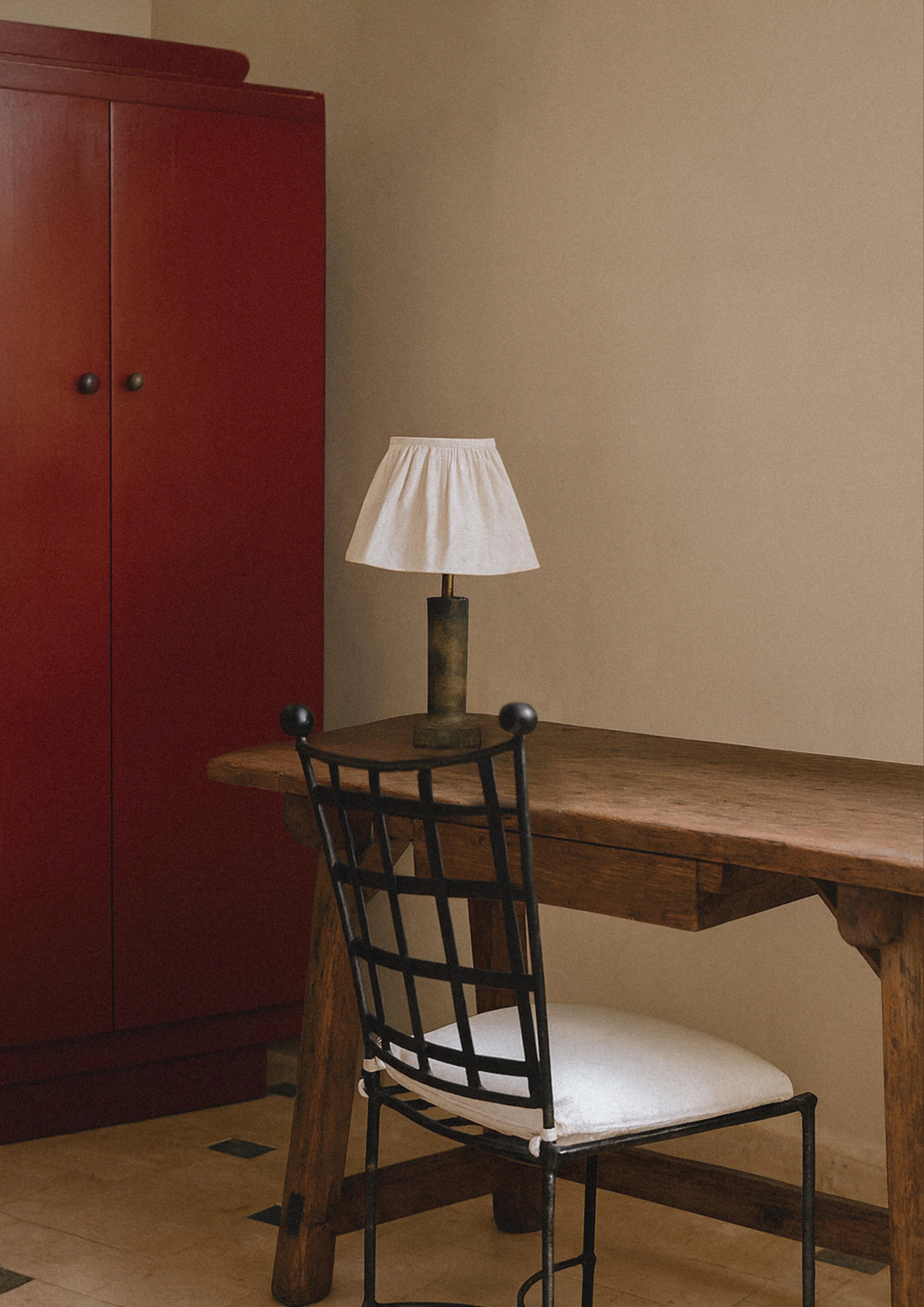 a vintage wooden desk with iron chair and red lacquered cabinet on the background