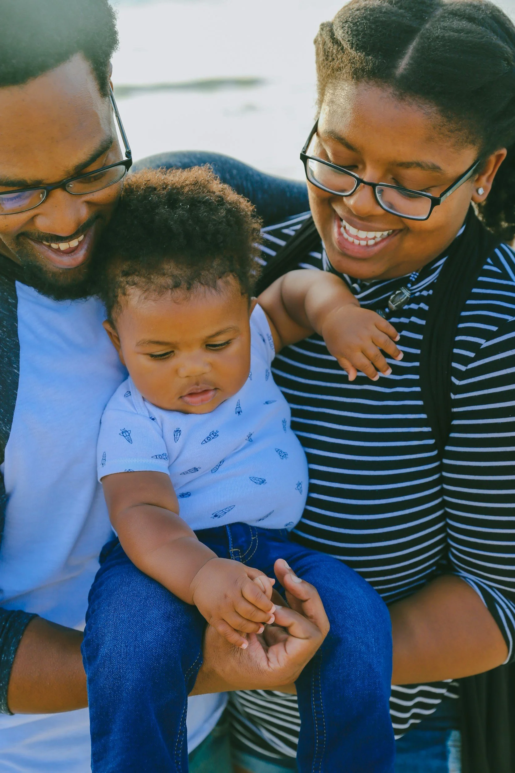 Two people holding a baby and smiling.