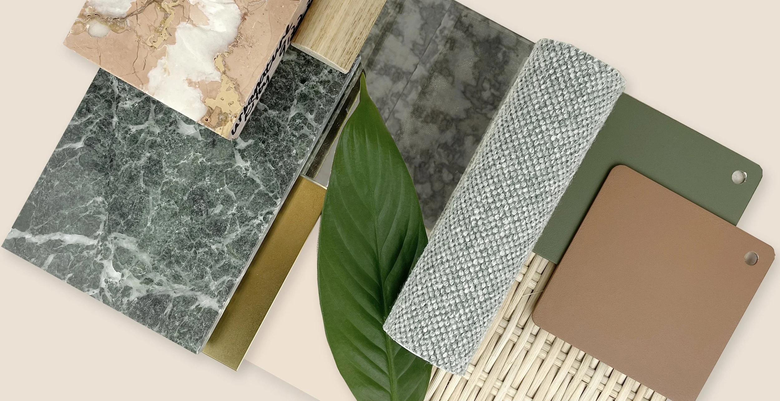A collection of various material samples including marble, wood, fabric, metal, and plastic with some green leaves for decoration.