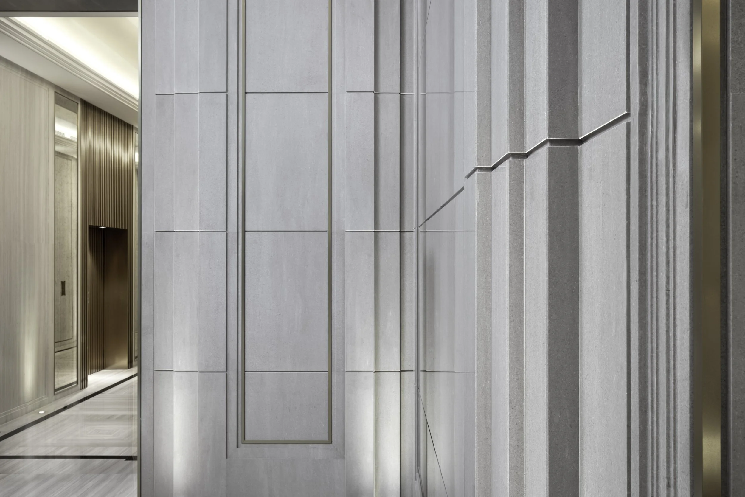 Modern building interior with gray wall panels and hallway with beige walls and wooden accents.
