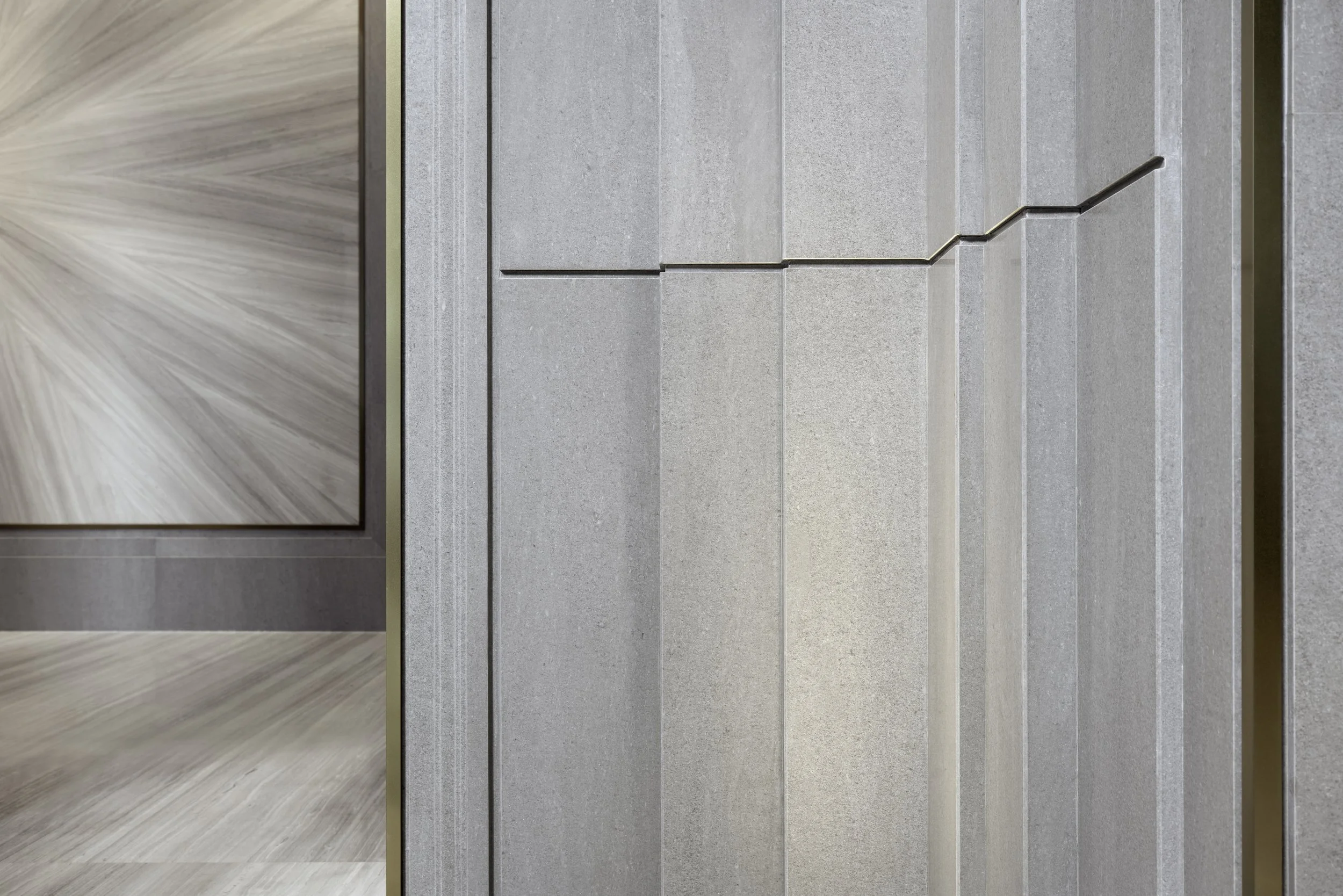 Gray elevator interior with textured wall panels and stainless steel handrail.