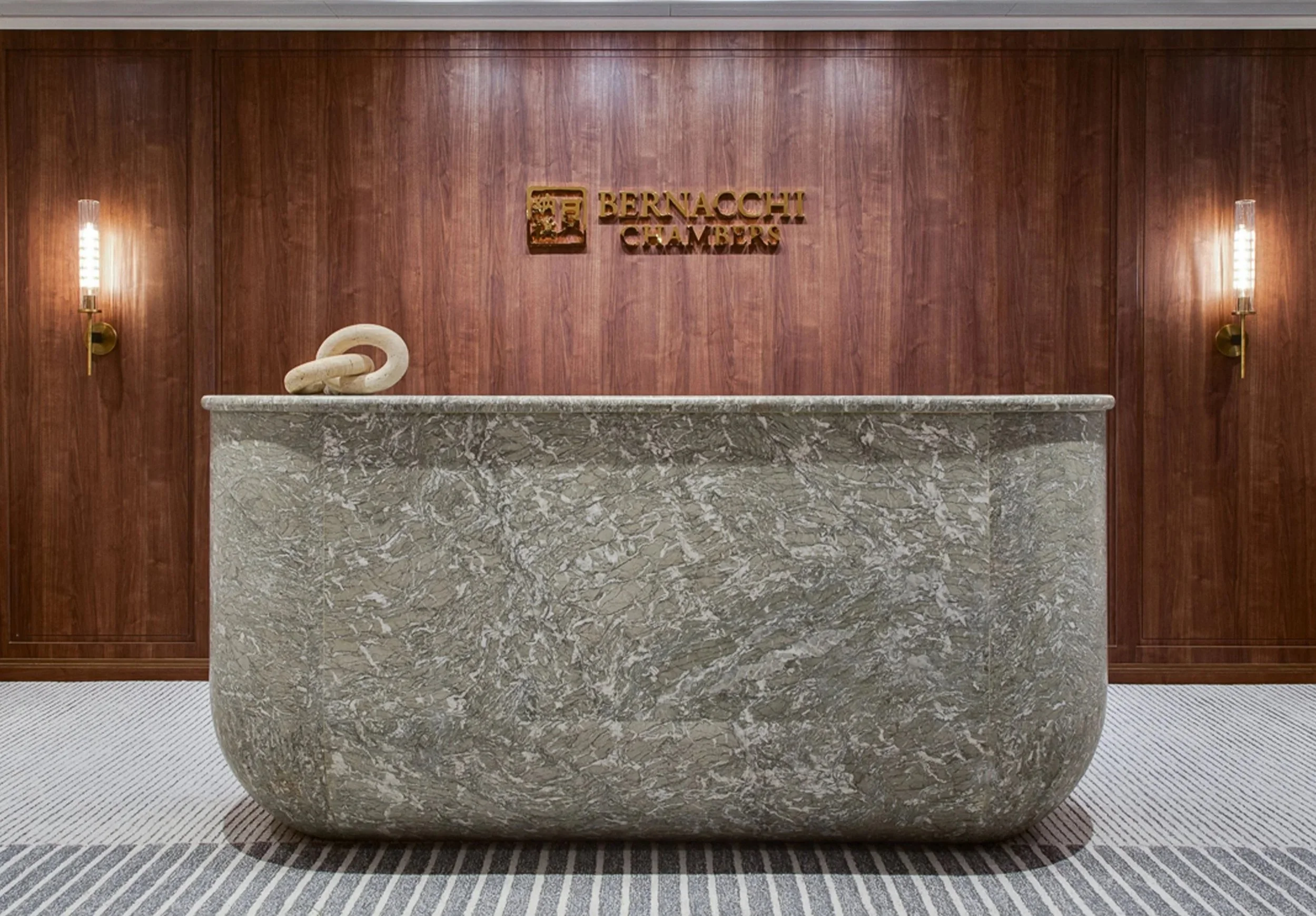 Reception desk in front of a wood-paneled wall with the Bernach Chambers logo.