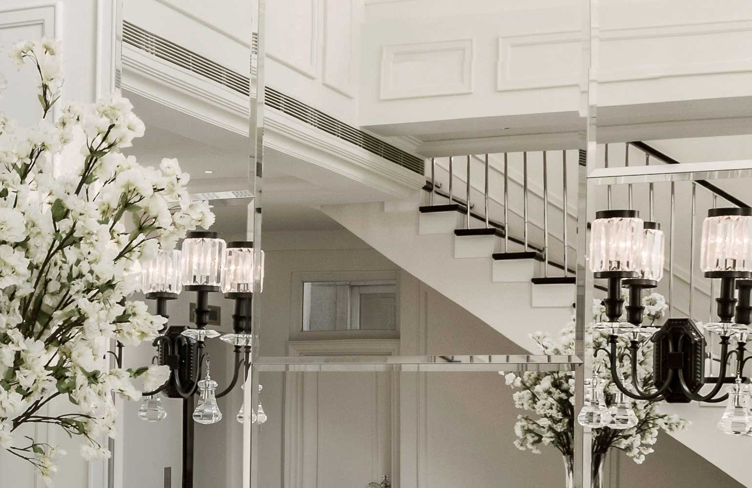 Interior view of a modern, luxury home with a staircase, decorative lighting, and floral arrangements in vases.