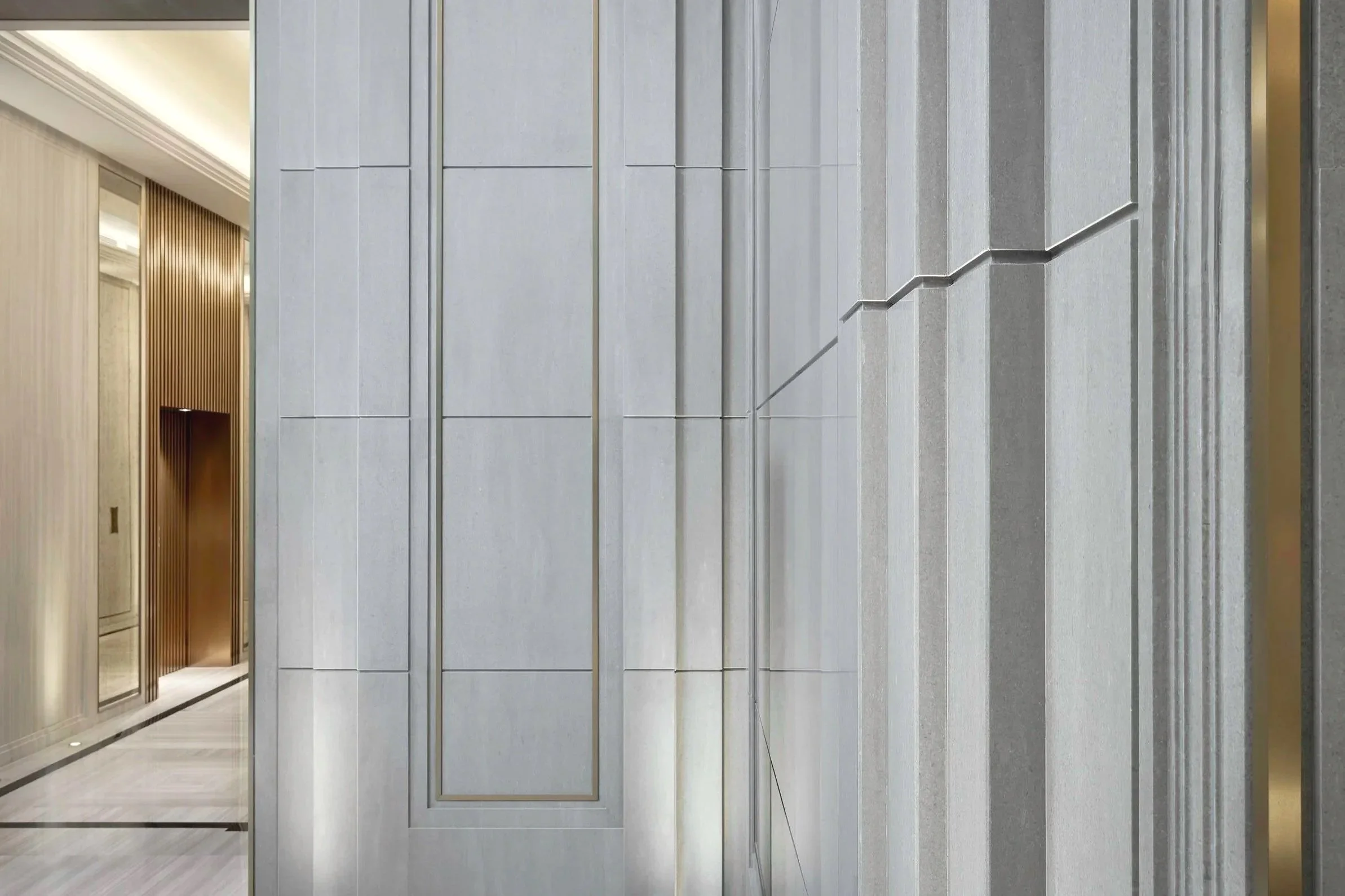 Elevator doors in a modern building lobby with decorative wall panels and wood accents.