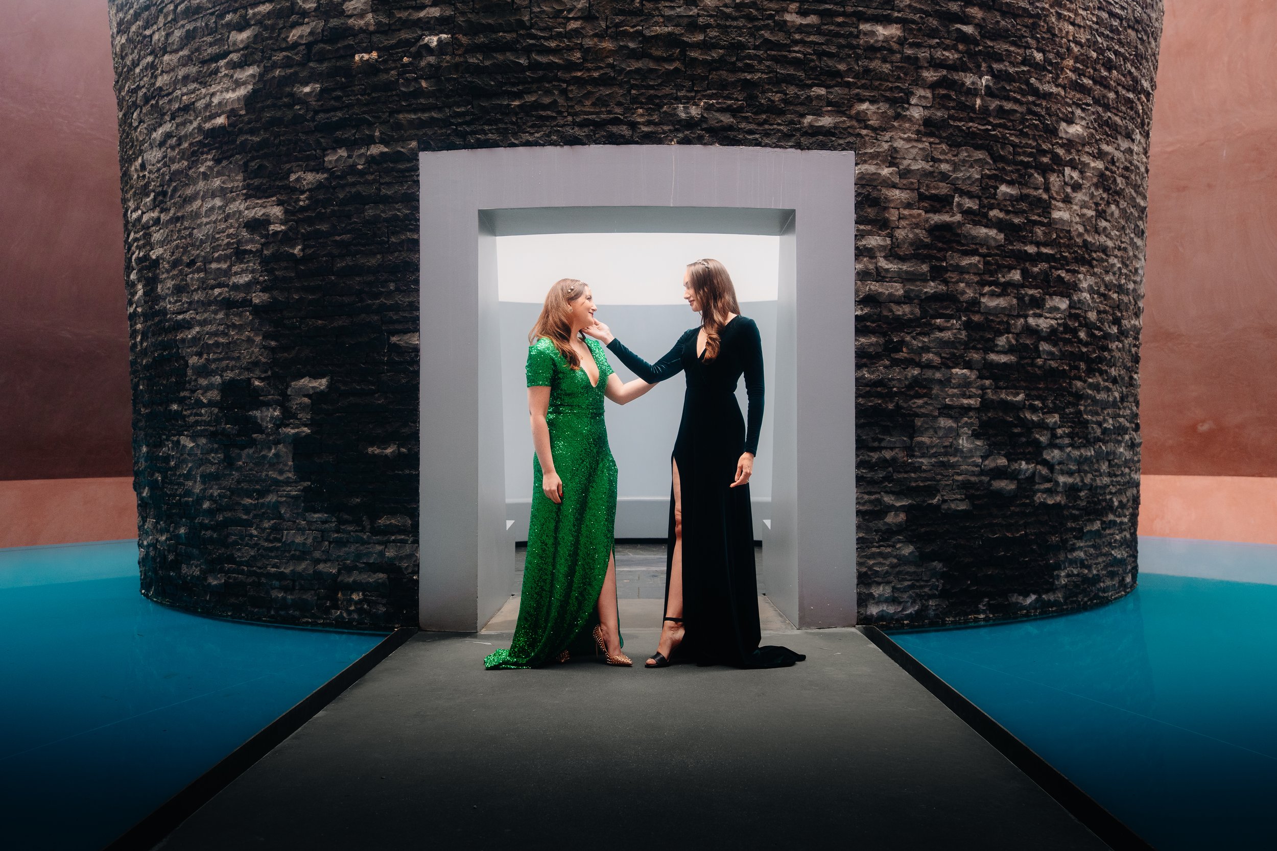 Lifestyle Photography | Two fashionable women standing inside a modern, cylindrical stone structure with a white rectangular opening. minimal, artistic and clean vogue style photography.