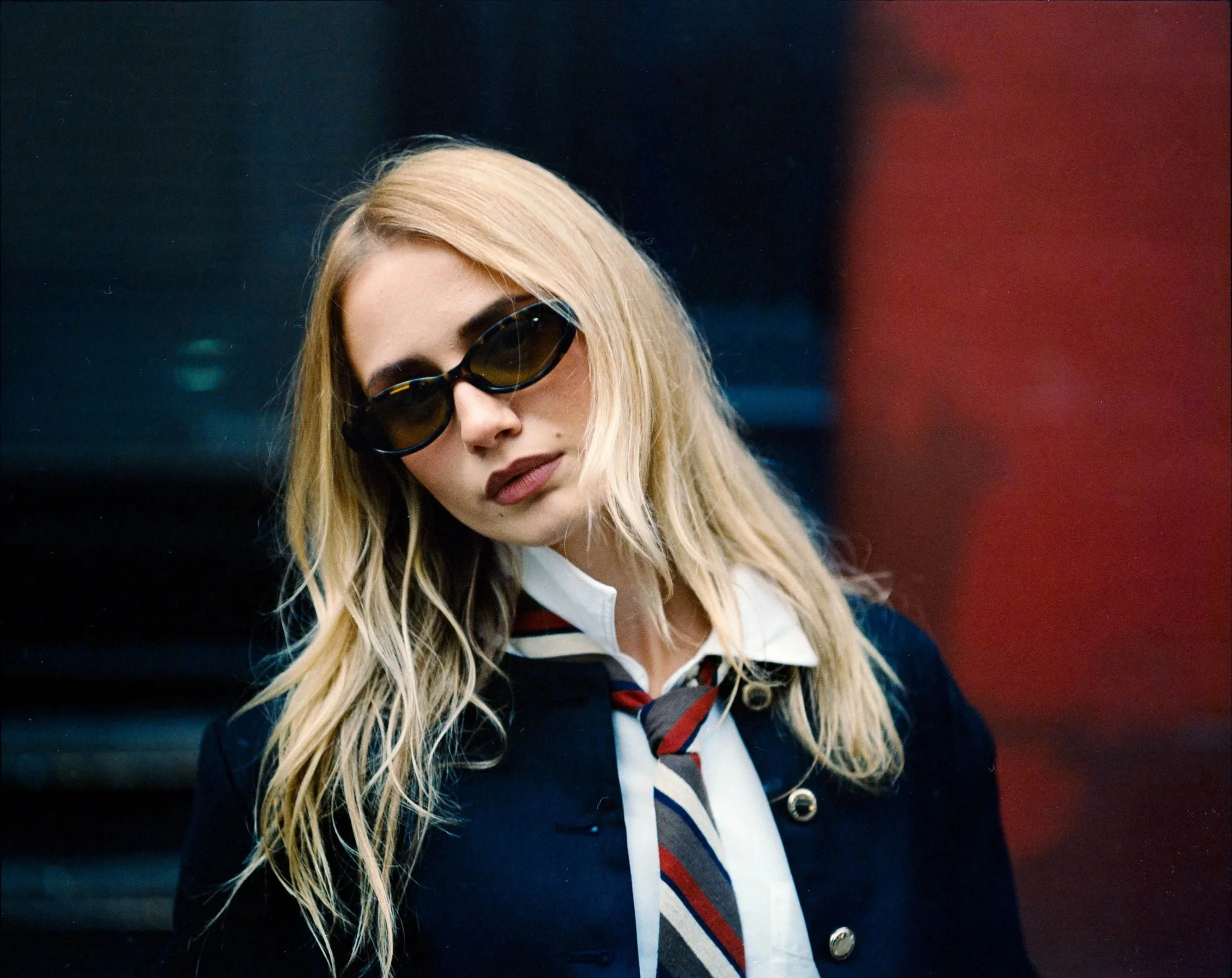Helga London in sunglasses, navy blazer and striped tie, New York City portrait
