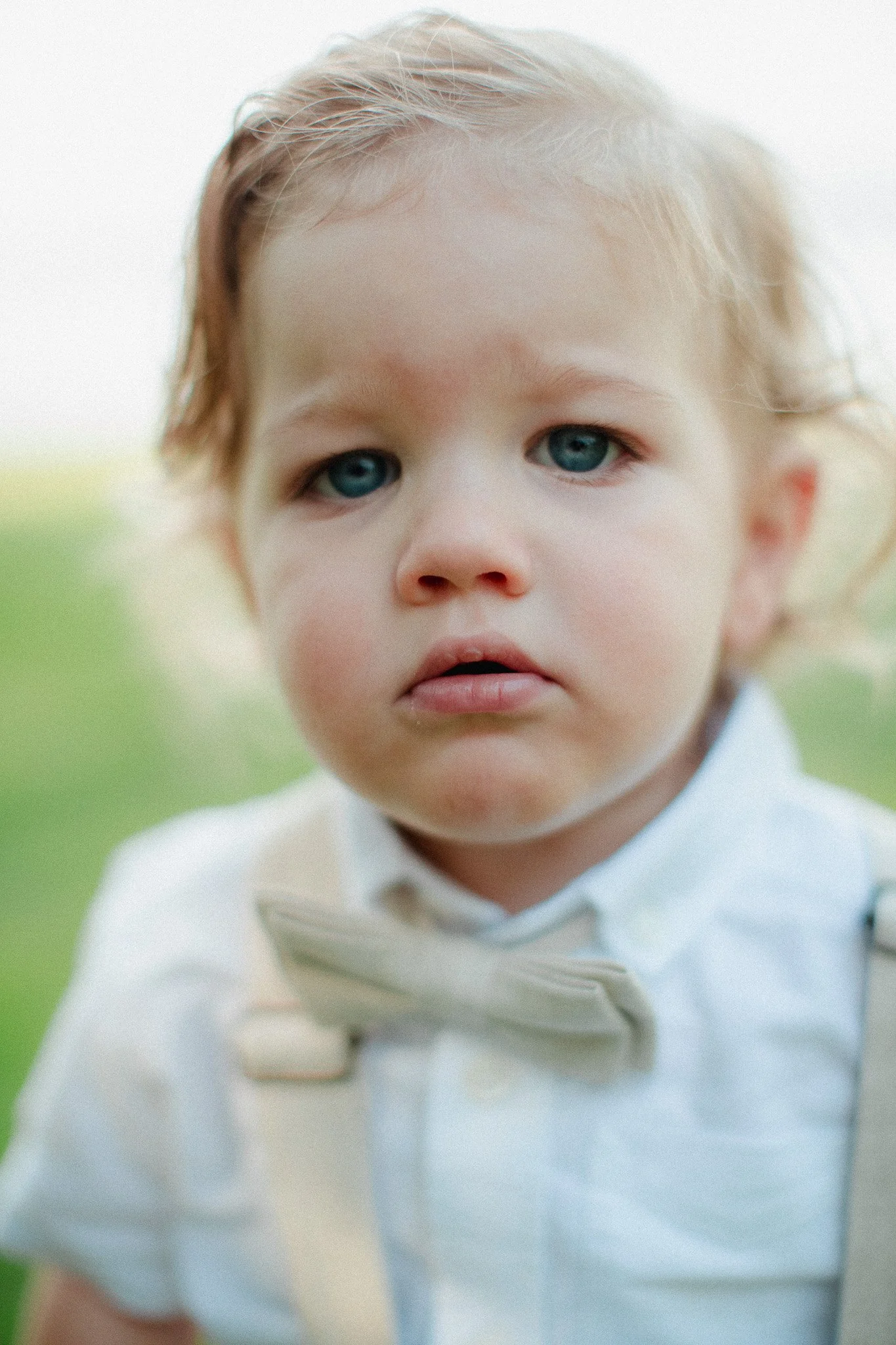 Close-up of a toddler ring bearer in a bow tie and suspenders