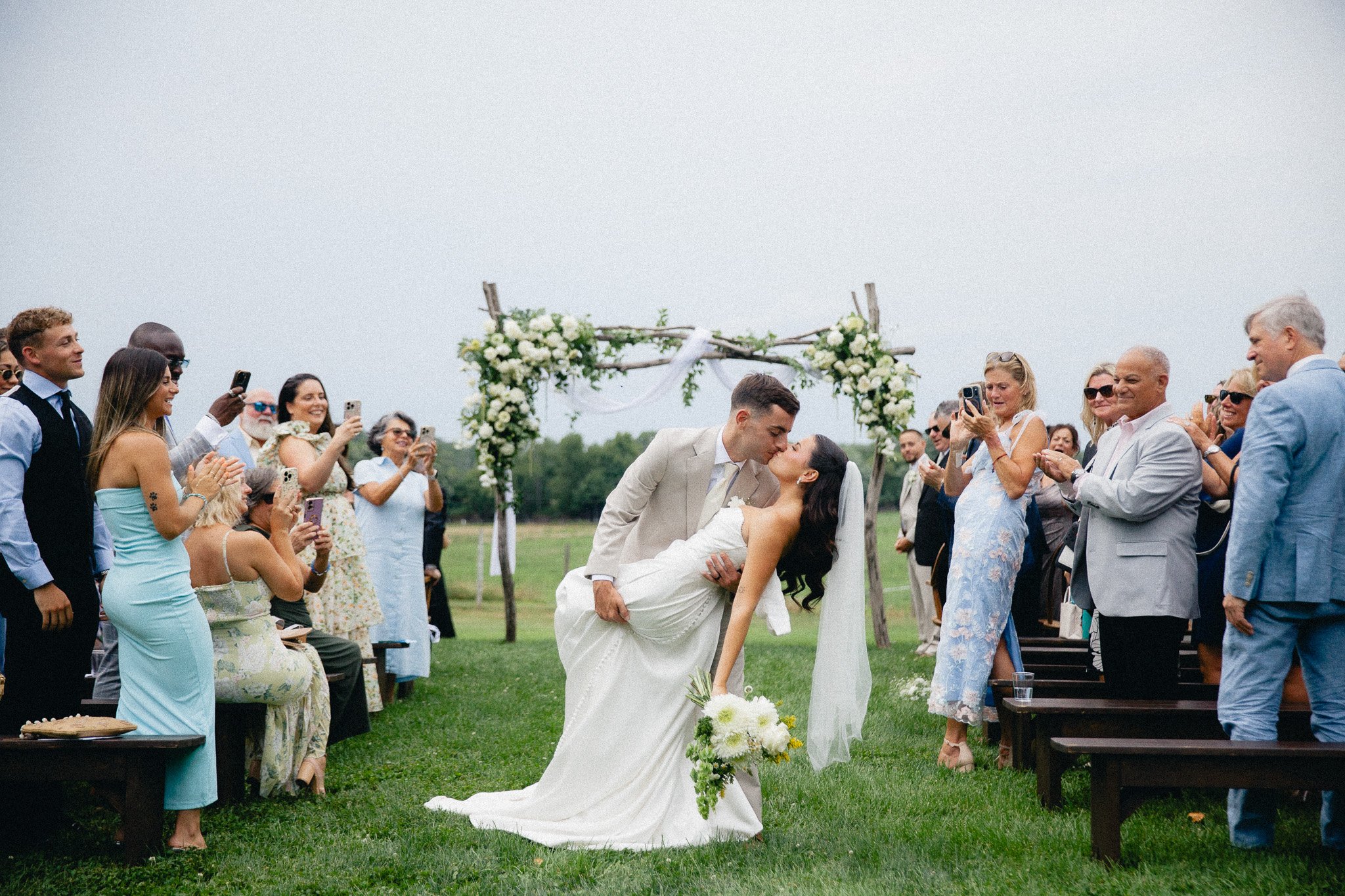Groom dipping the bride for a kiss at the end of the aisle, outdoor ceremony