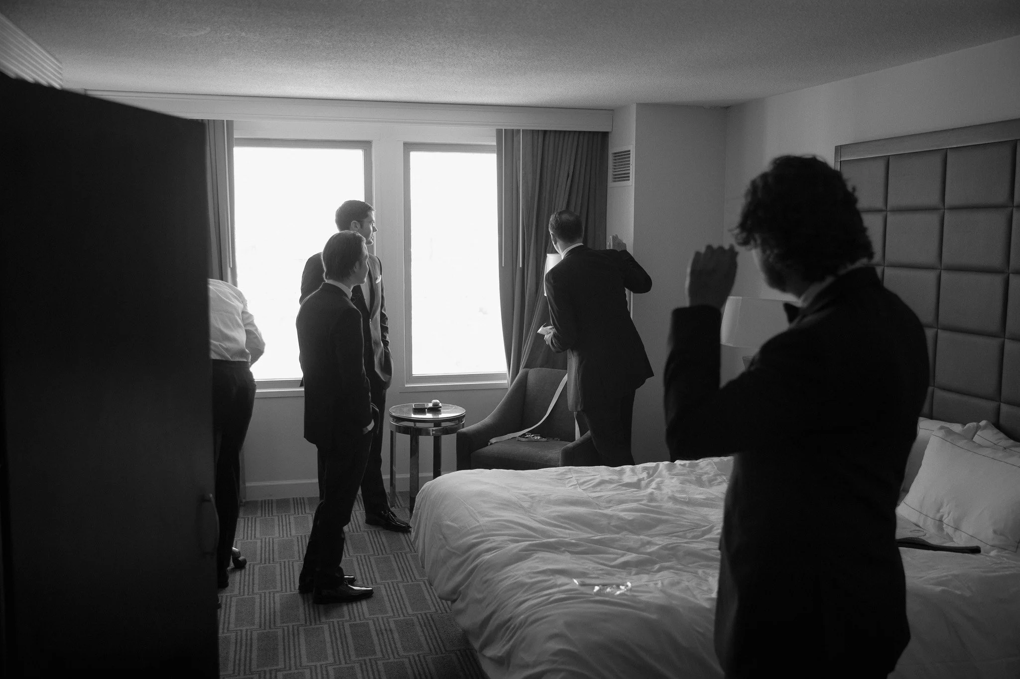 Groom and groomsmen getting ready in a hotel room, black and white wedding photography