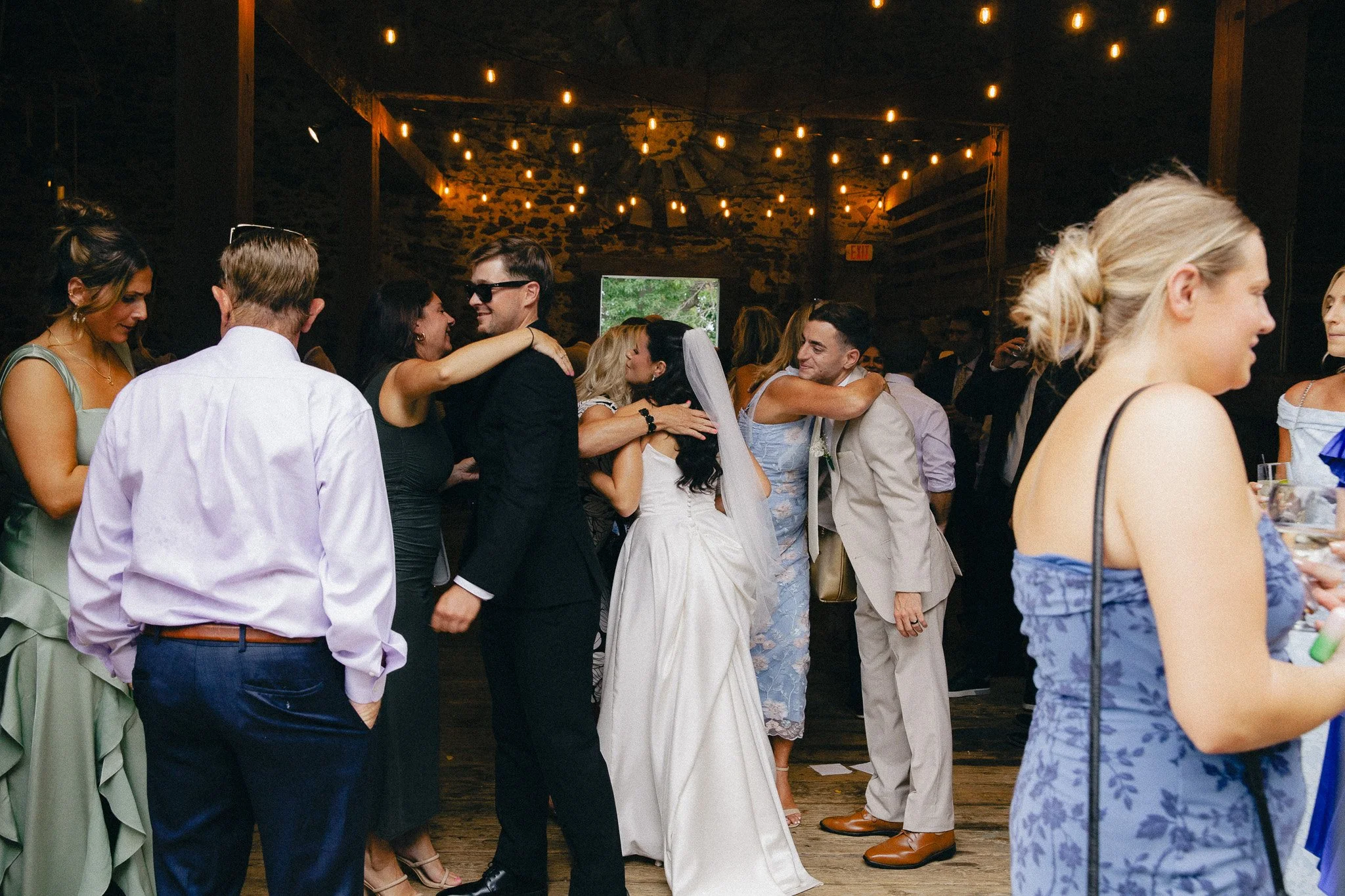 Wedding guests dancing under string lights at an evening barn reception
