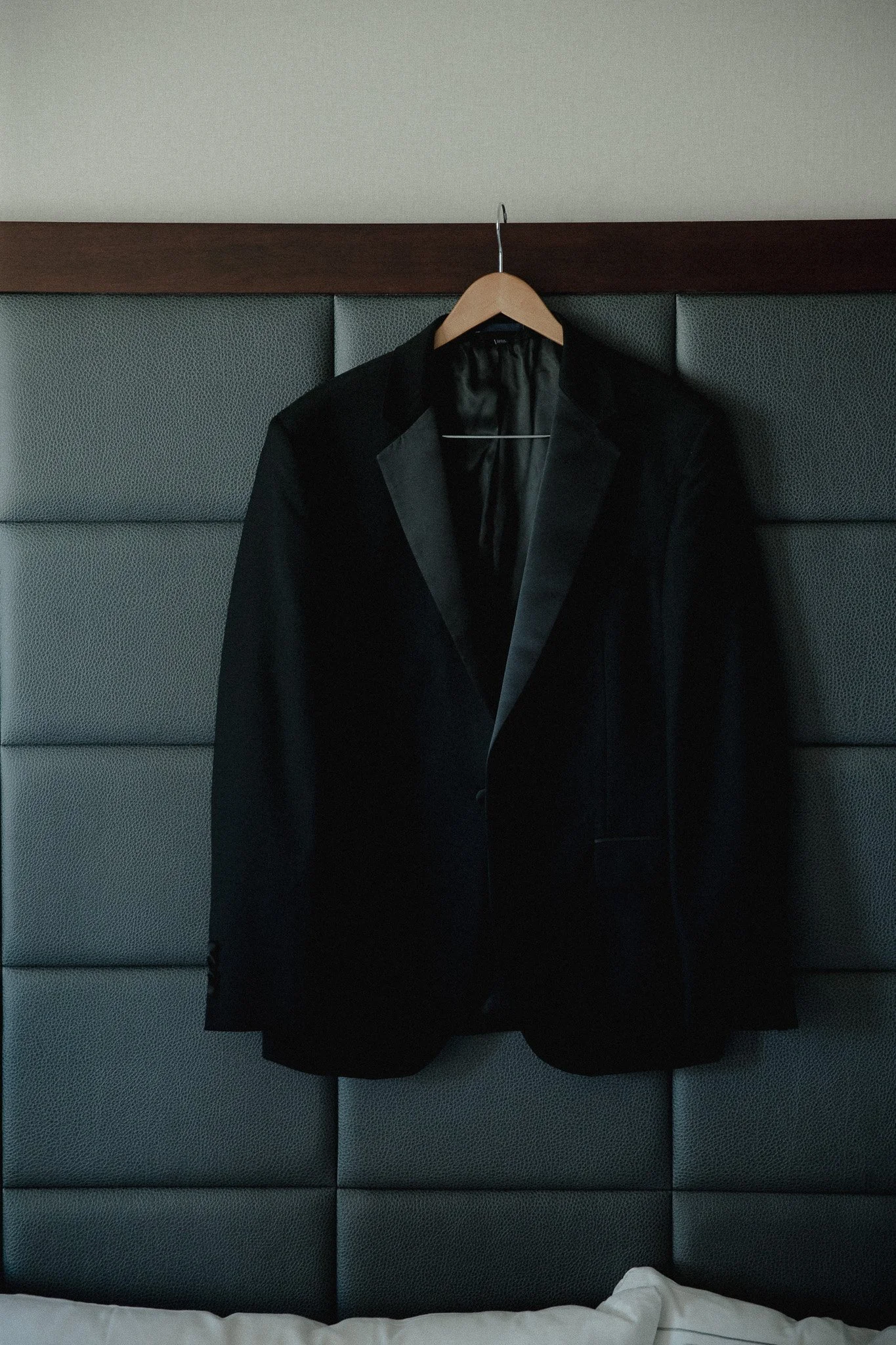 Black tuxedo jacket hanging on a padded headboard before the wedding