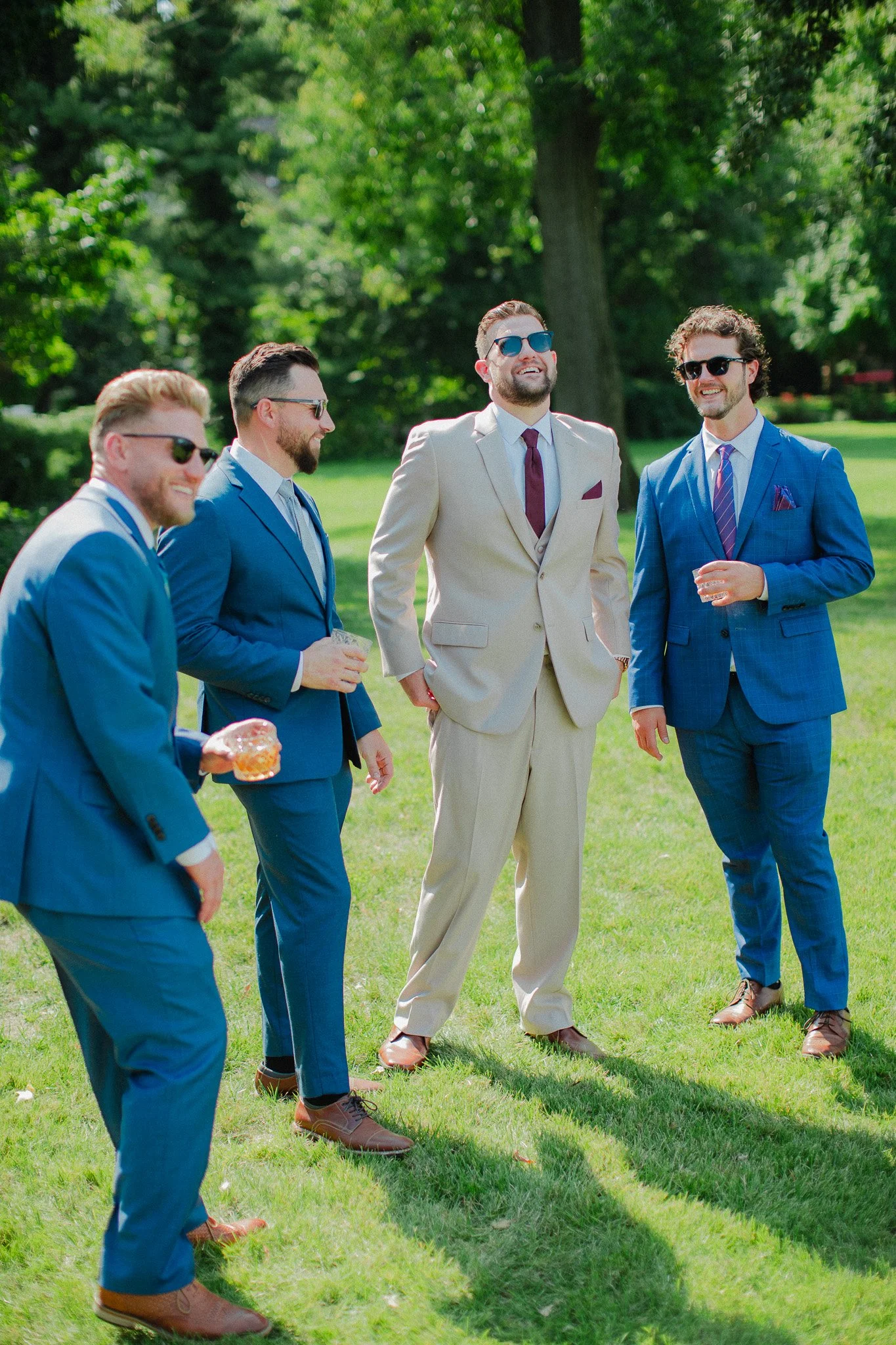 Groom and groomsmen in blue suits laughing together on the lawn