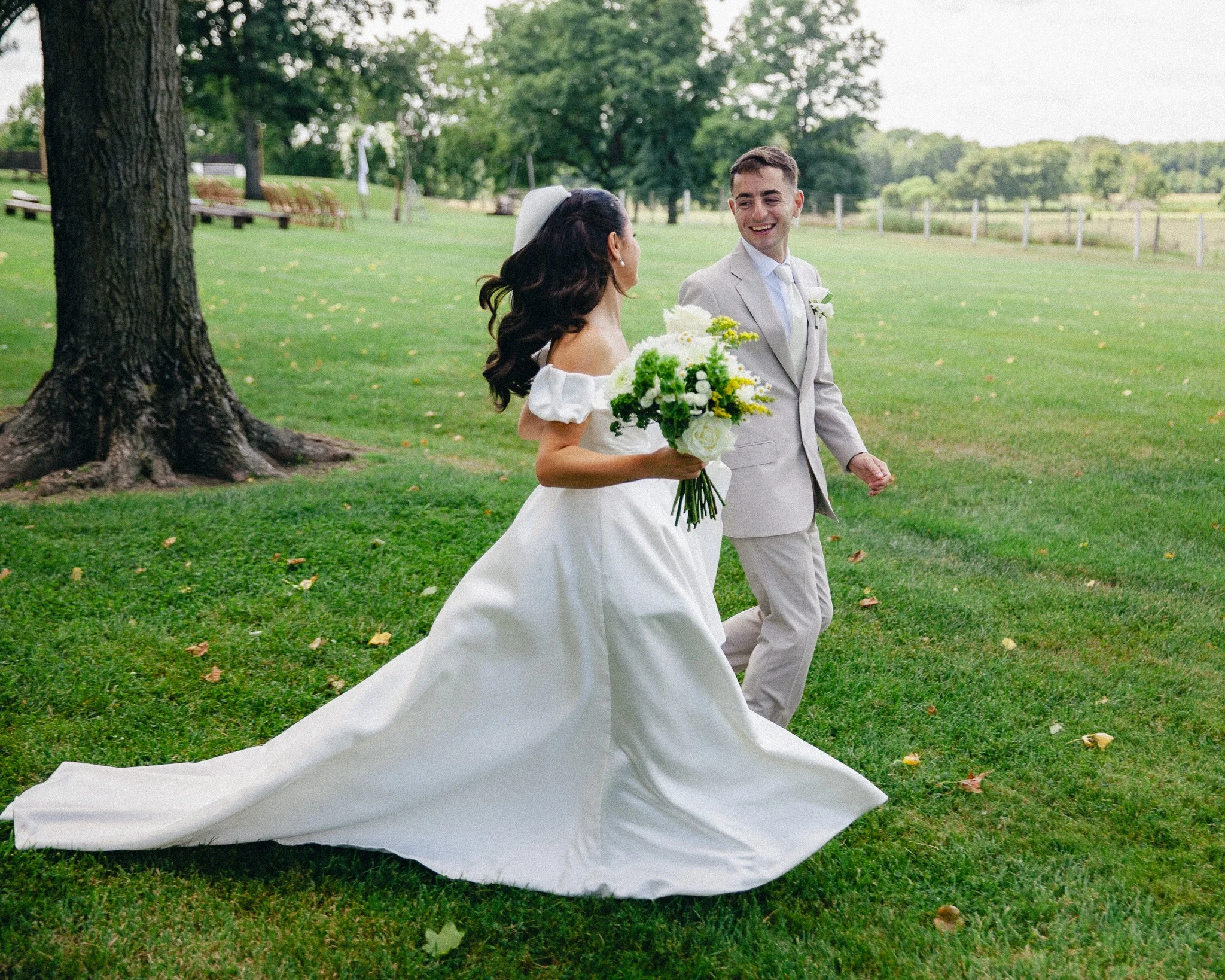 Bride and groom walking hand in hand across a sunny lawn, New Jersey wedding