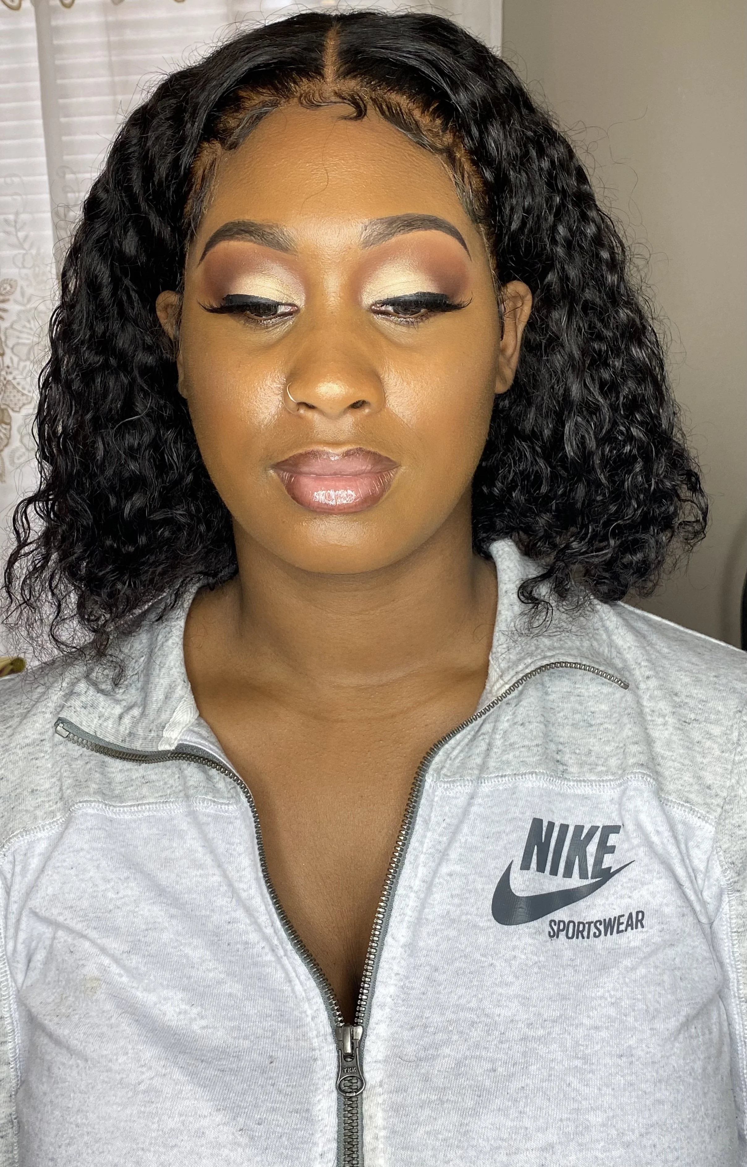 Person with curly hair, and wearing makeup 