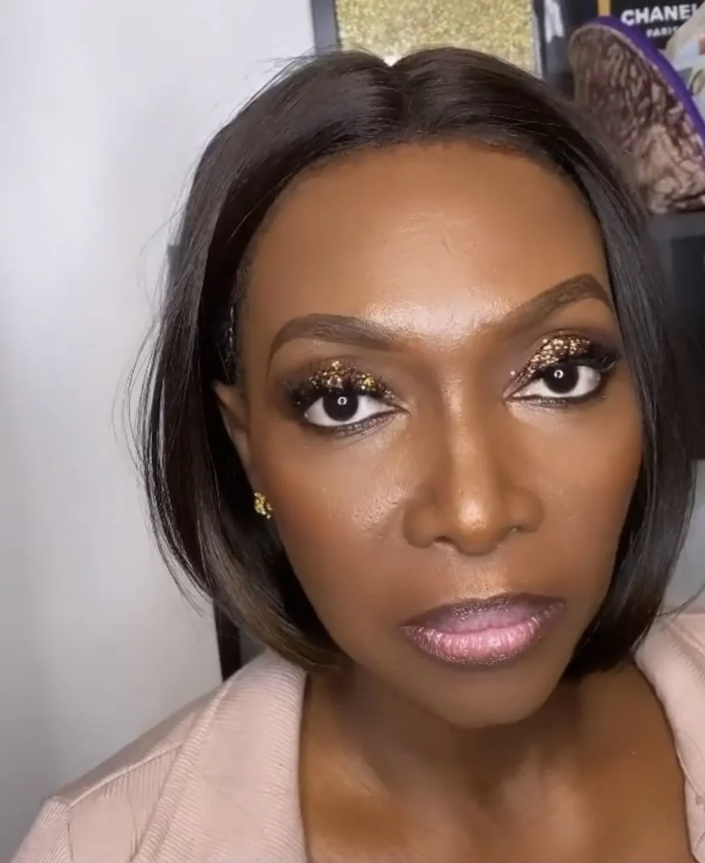 Close-up of a person with glittery eye makeup and a serious expression.