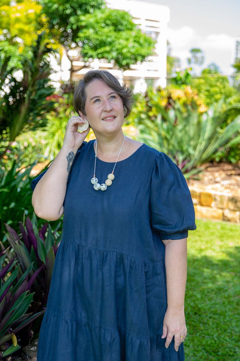 Conni Warren standing outdoors in a garden setting, reflecting calm, approachable and professional presence