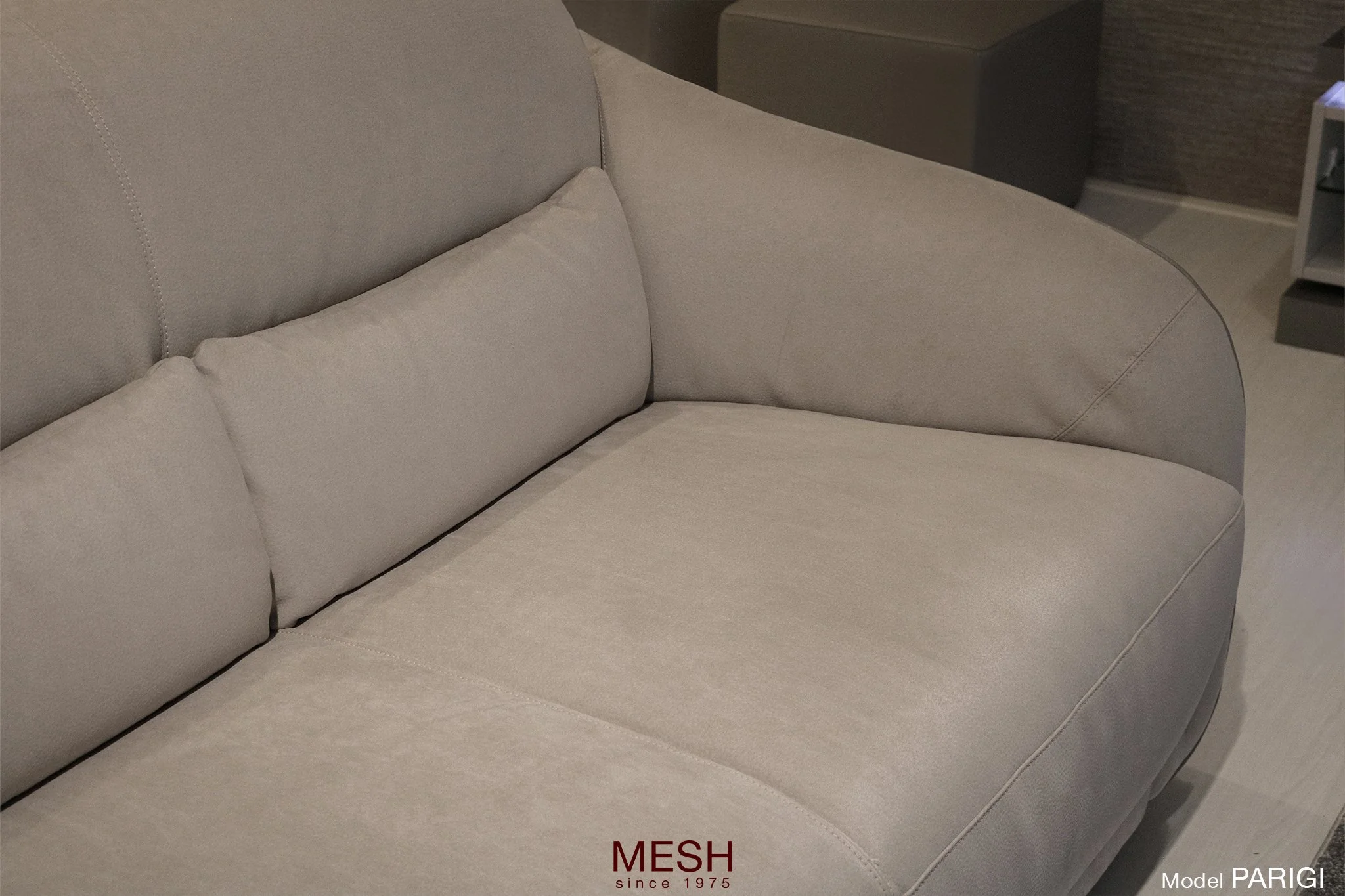 Een beige stoffen bank met een rechte rugleuning en bijpassende kussens in een woonkamer.
