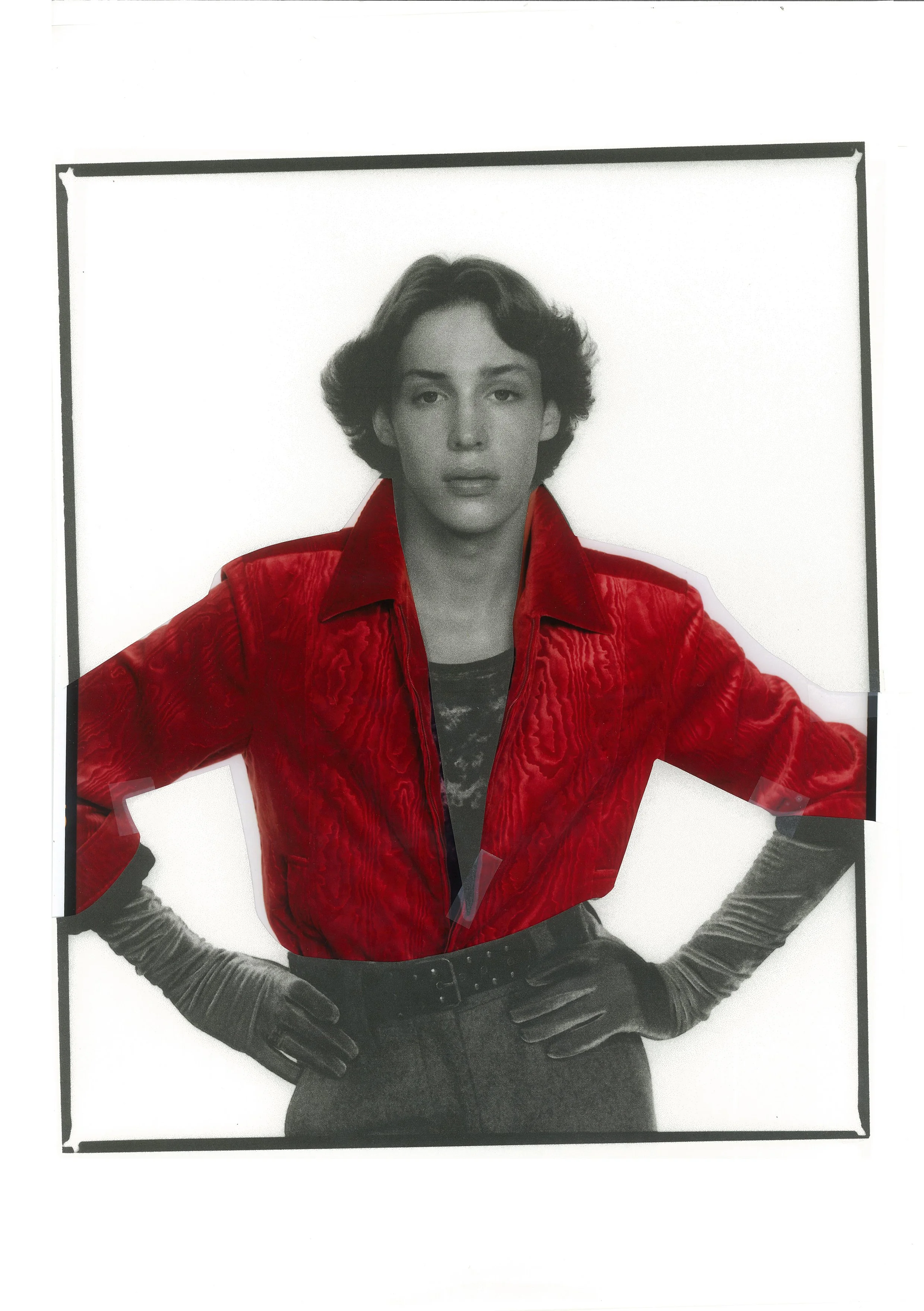 Black and white photo of a person with a digitally colored red jacket, hands on hips, neutral expression.