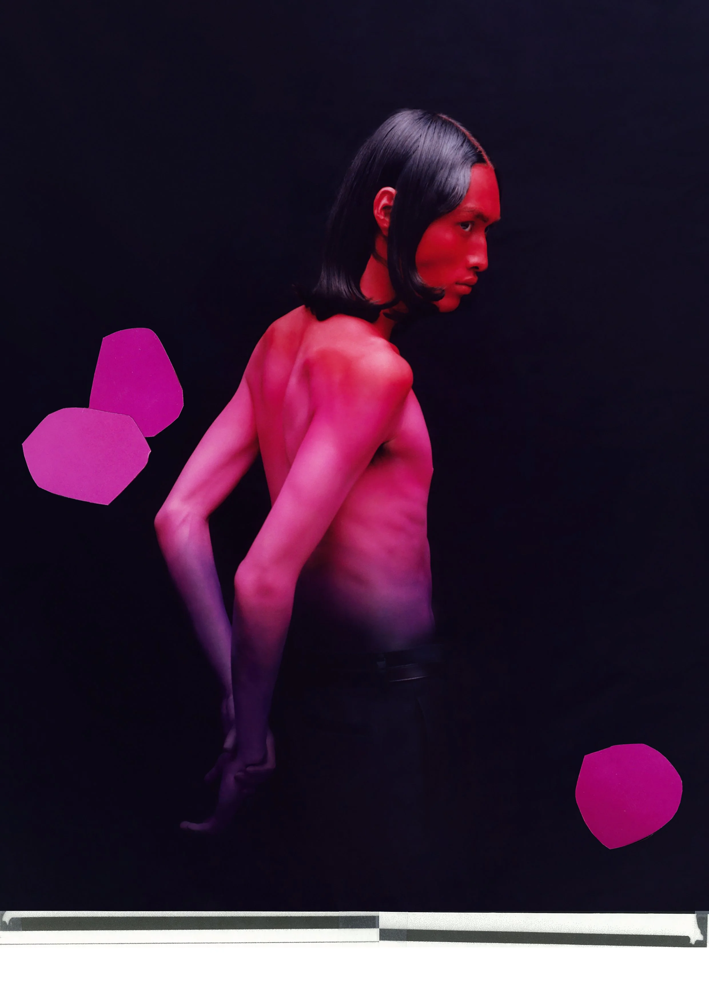 Person with long hair and bare back in pink lighting against a dark background.