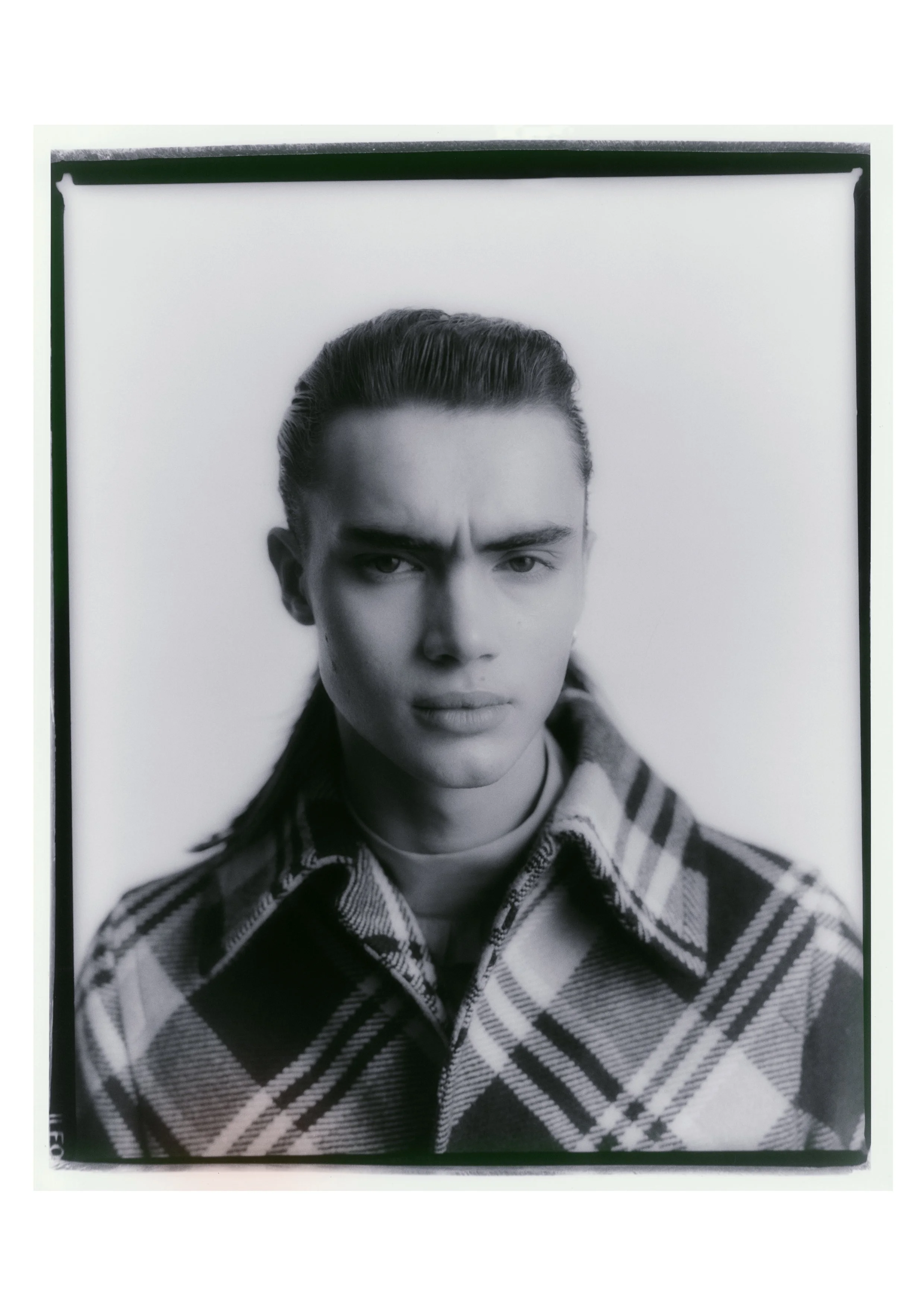 Black and white portrait of a person wearing a plaid jacket.