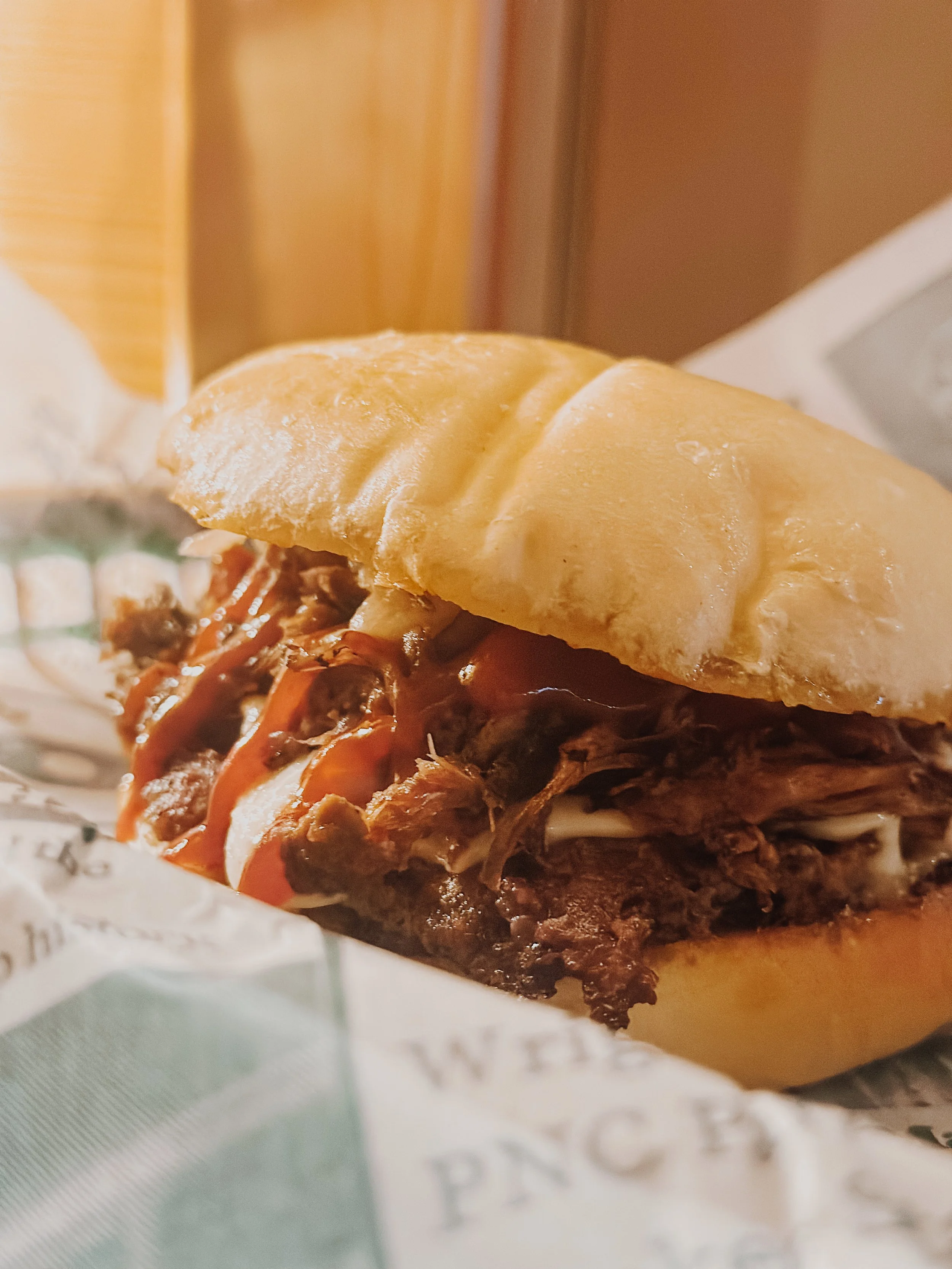 Close-up of a pulled pork sandwich with barbecue sauce, shredded pork, and a sandwich bun.