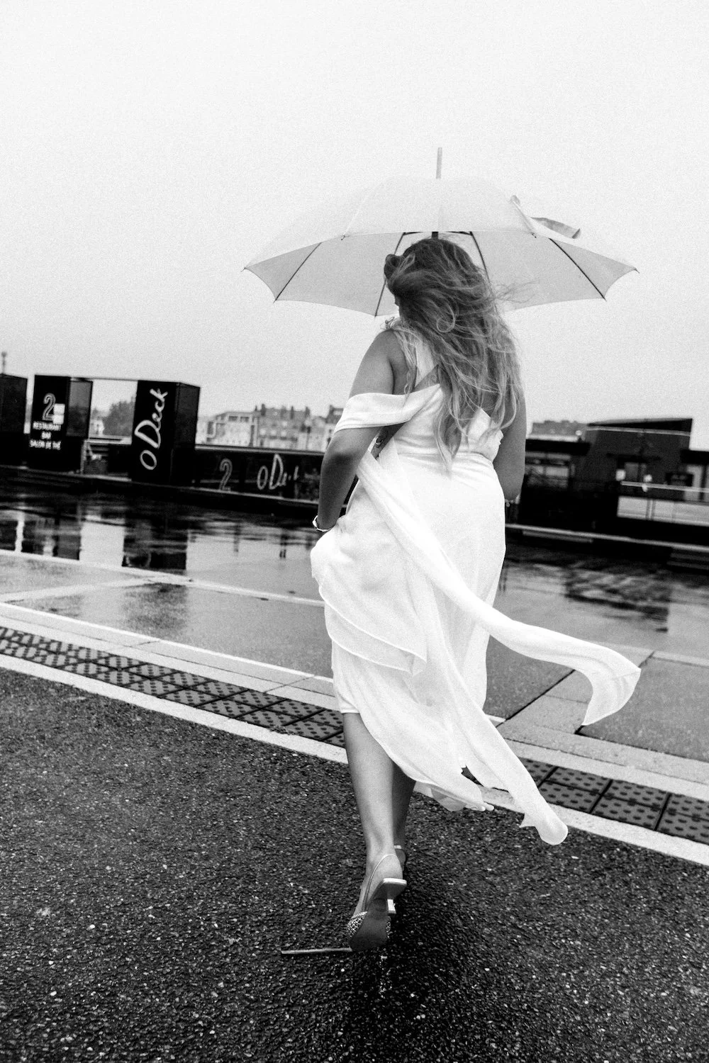 Mariée sous la pluie et son parapluie transparent au O'Deck à Nantes par le photographe François Mougel.