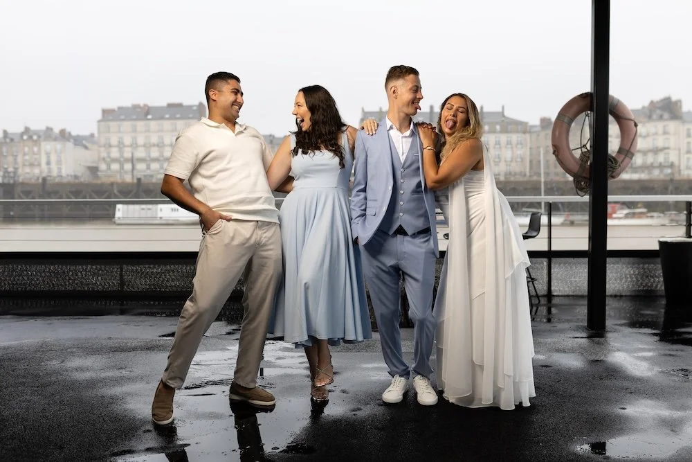Cinq amis souriants et riant, posant ensemble à l'intérieur avec vue sur la ville en arrière-plan.