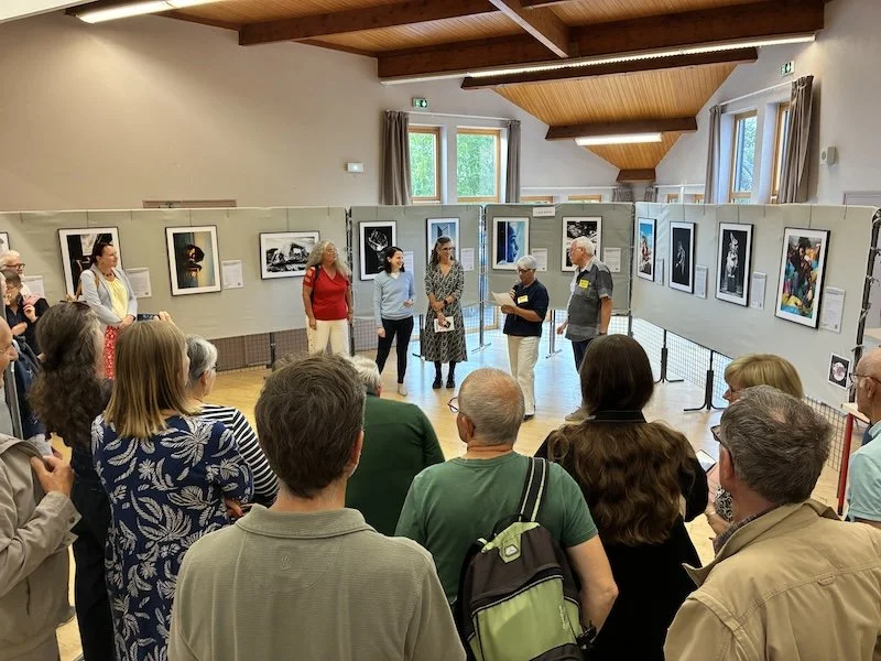 Vue générale de la salle d'exposition Les Équilibres Inconfortables à Nantes avec le public rassemblé autour des œuvres photographiques de François Mougel.