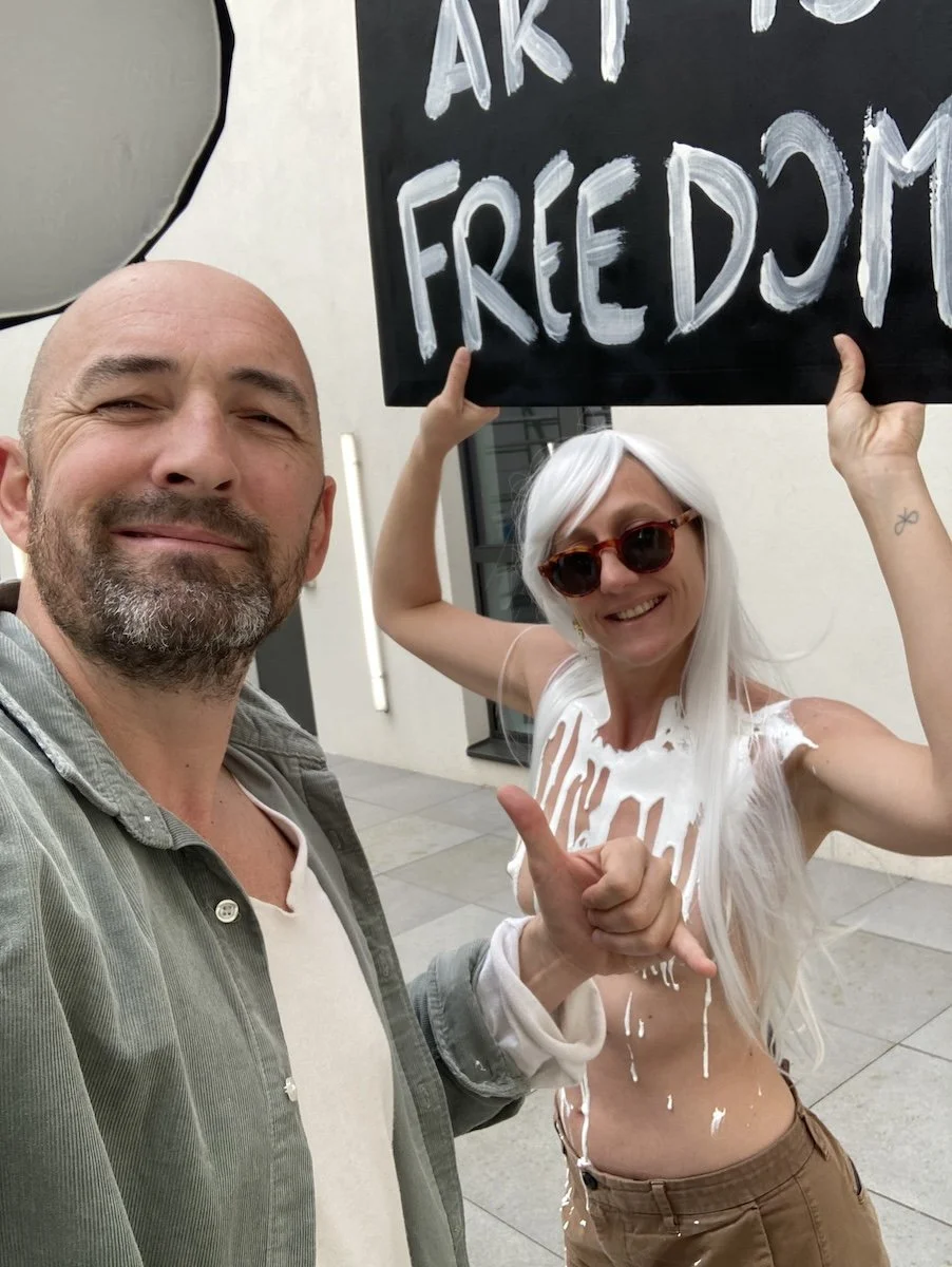 Photographe François Mougel en selfie aux côtés de la modèle photo Marie-Charlotte tenant un panneau Art is Freedom pendant un shooting.