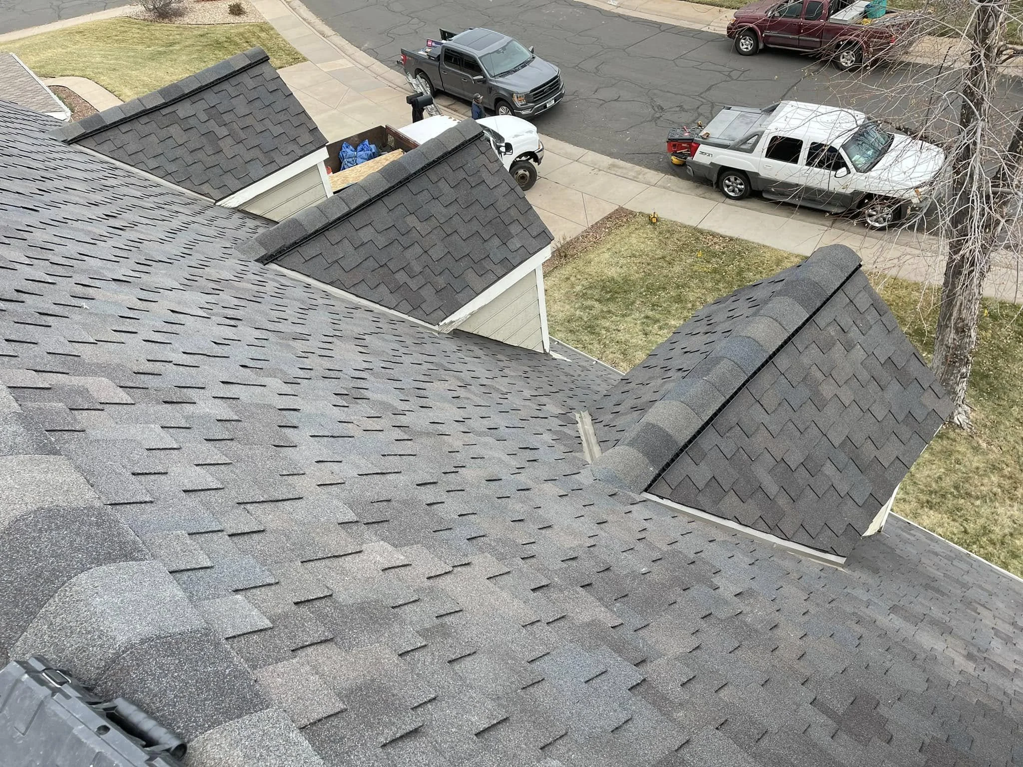 an example of roofing in Lakewood: grey asphalt shingles installed on a house with two pitched windows.