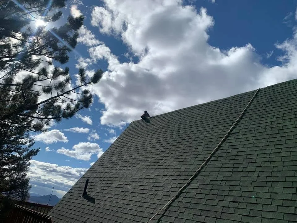 an example of roofing in Golden, CO: a steep gray roof photographed with a cloudy sky behind it.