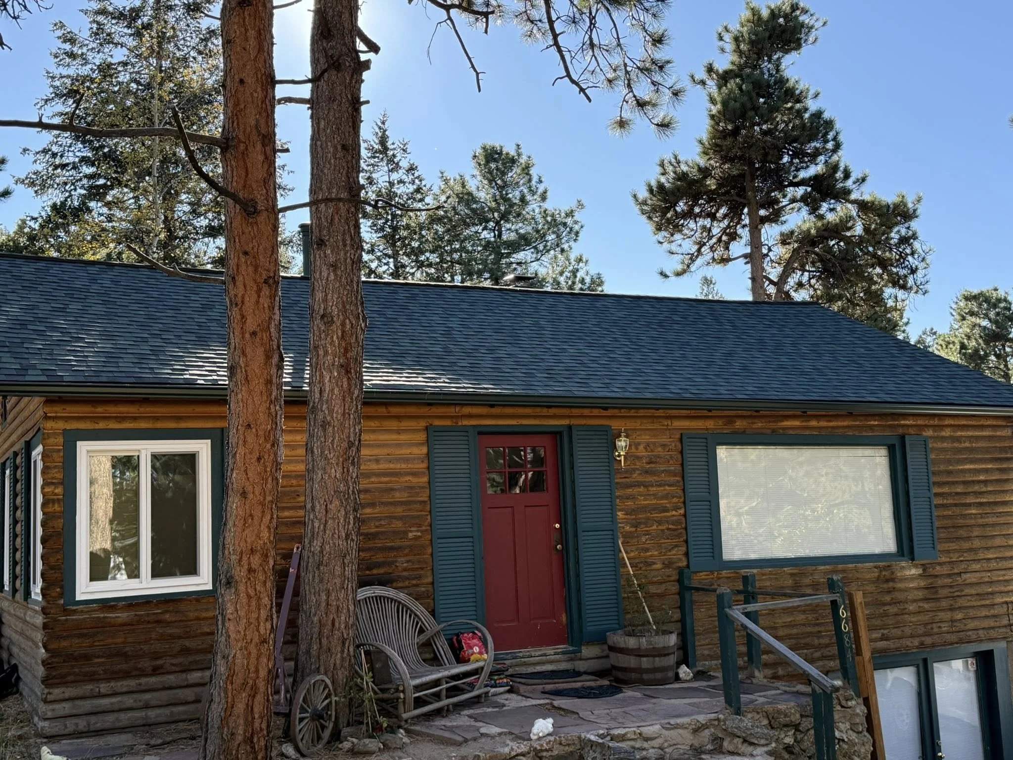 wood home with red door and grey roof | Roof replacement cost Evergreen, CO | Troost Roofing