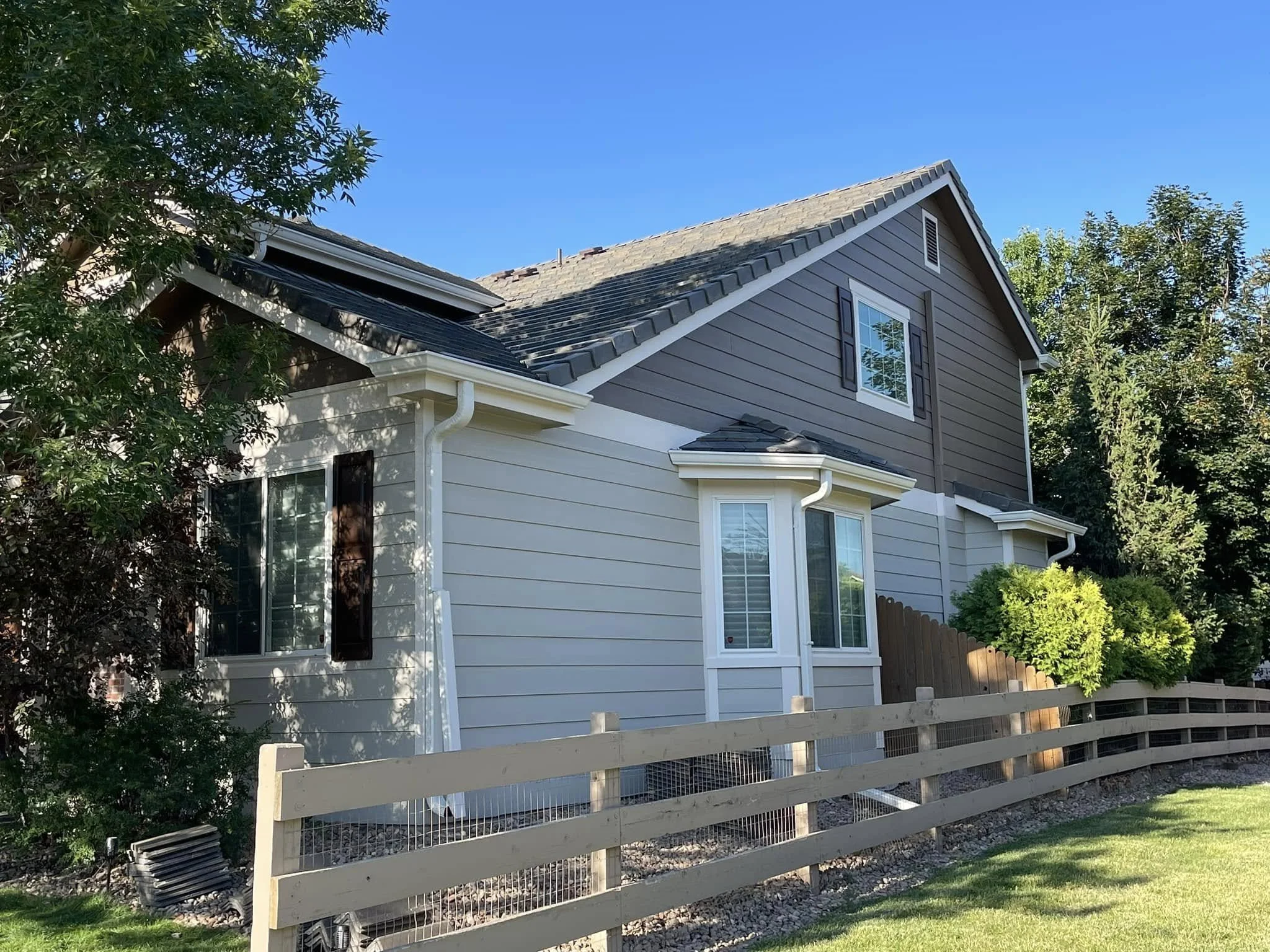 a home with Coal Creek roofing: gray slate roof on a beige and gray house.