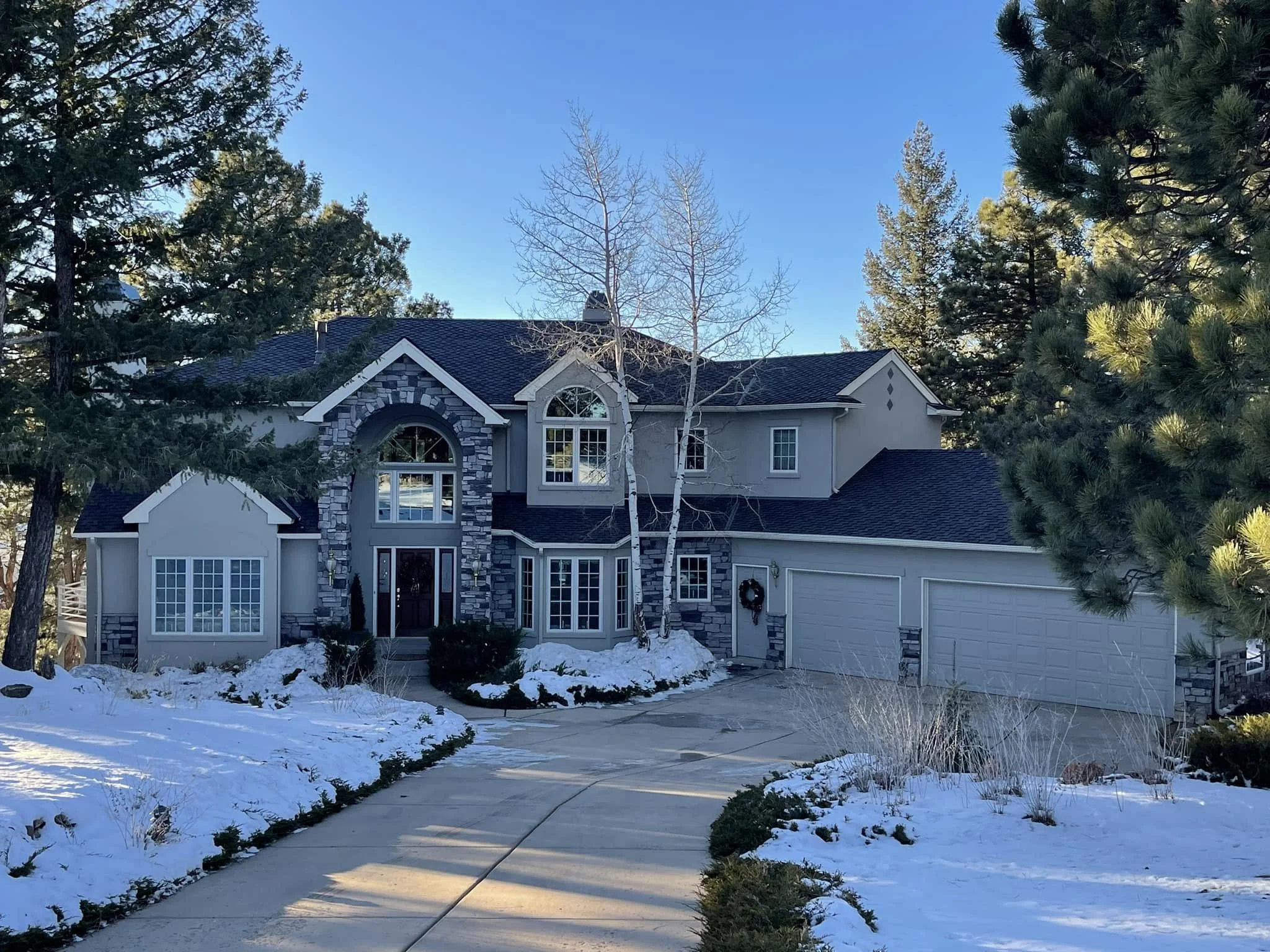 an example of roofing in Golden, CO: a large, grey, stone house with a fresh gray roof.