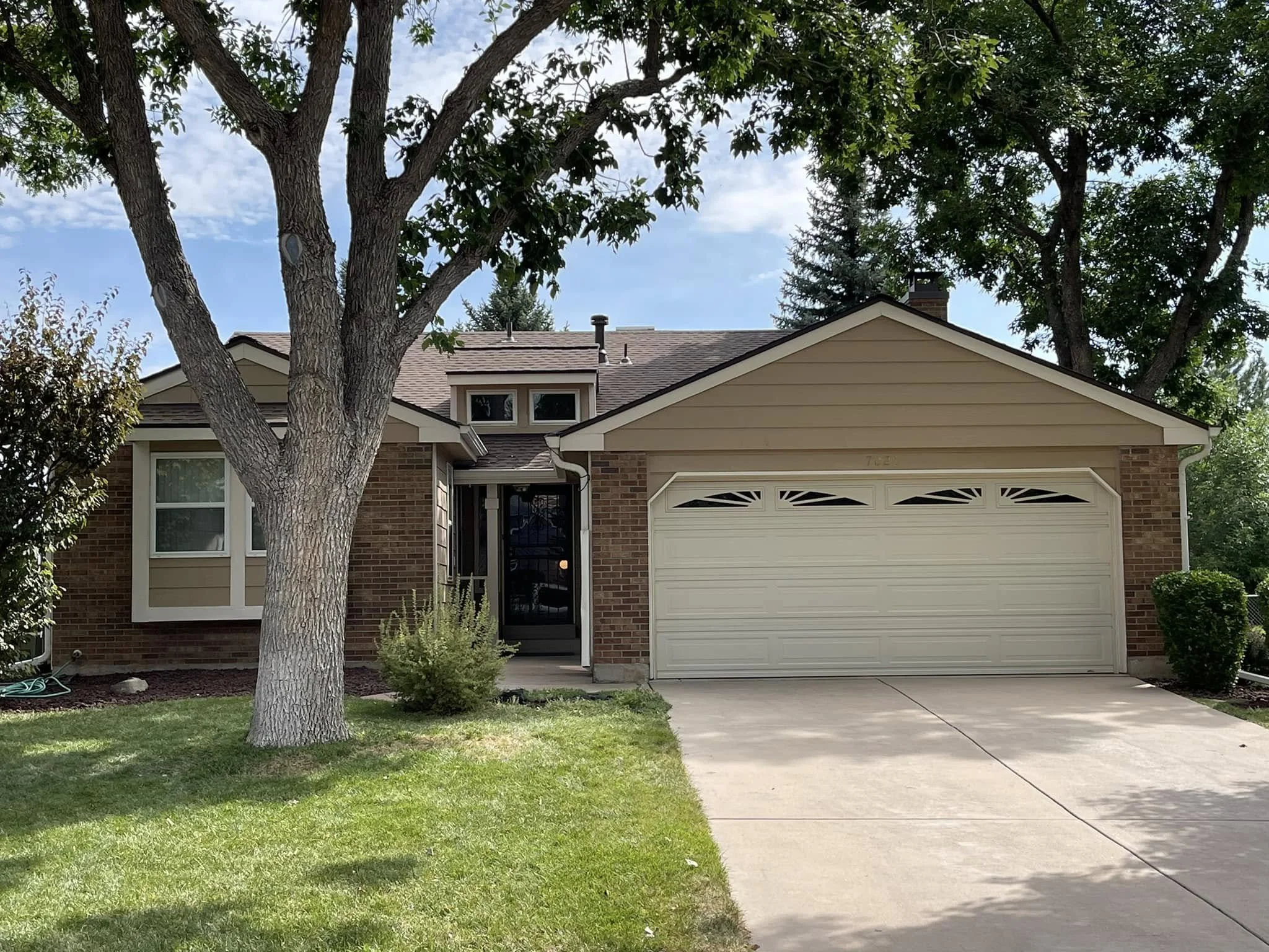 a light brown home with a white garage and a newly installed roof.