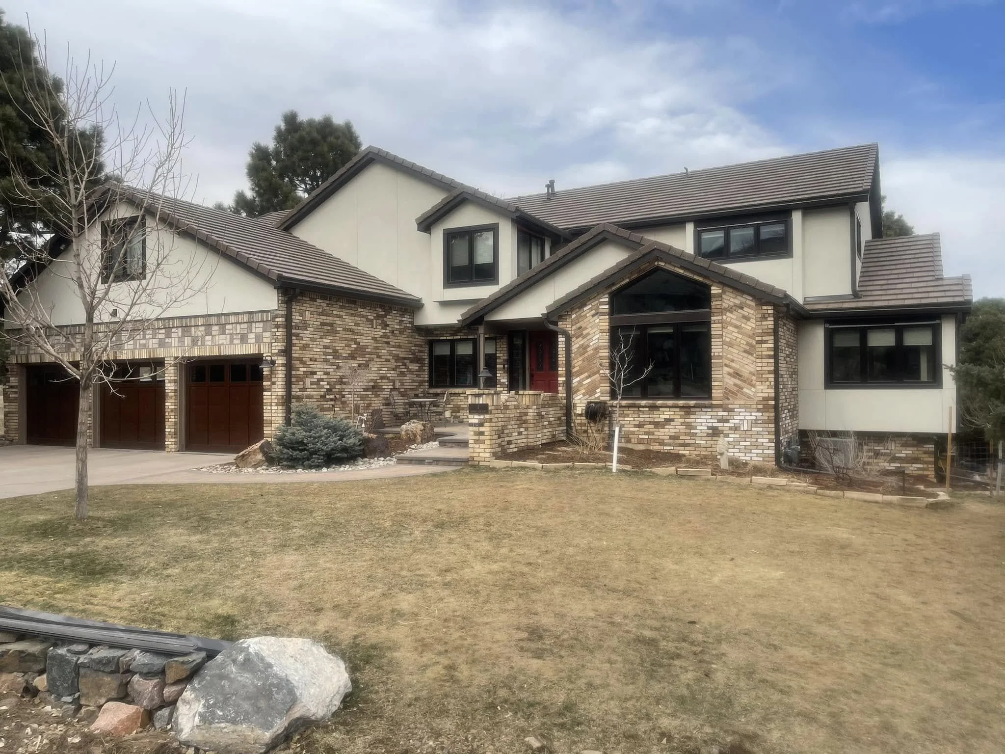 a large, stone home with Bailey, CO roofing styles: class 4, fire proof shingles on a white home.