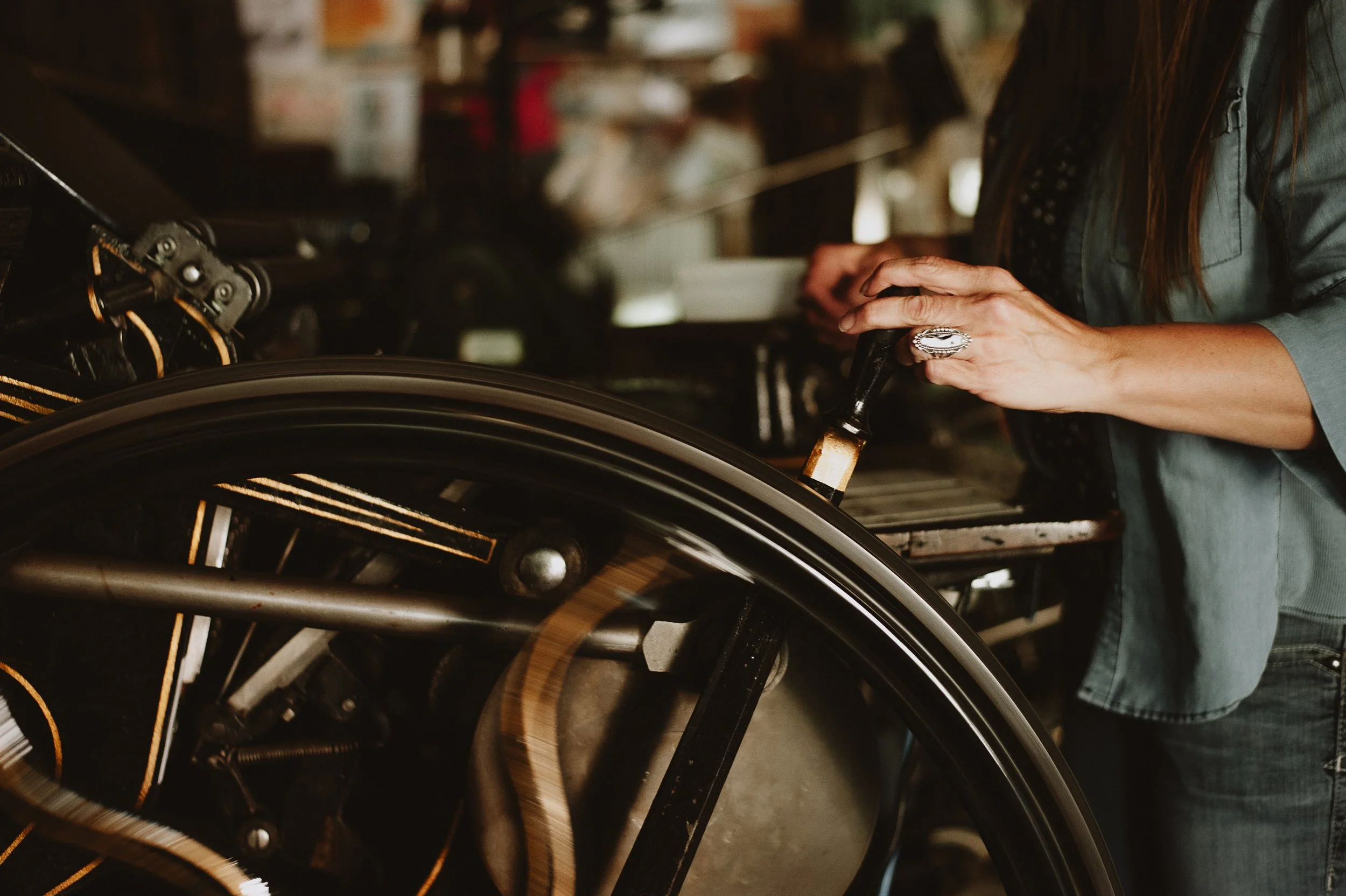 A person using a brush to polish or work on a wheelchair in a workshop setting.