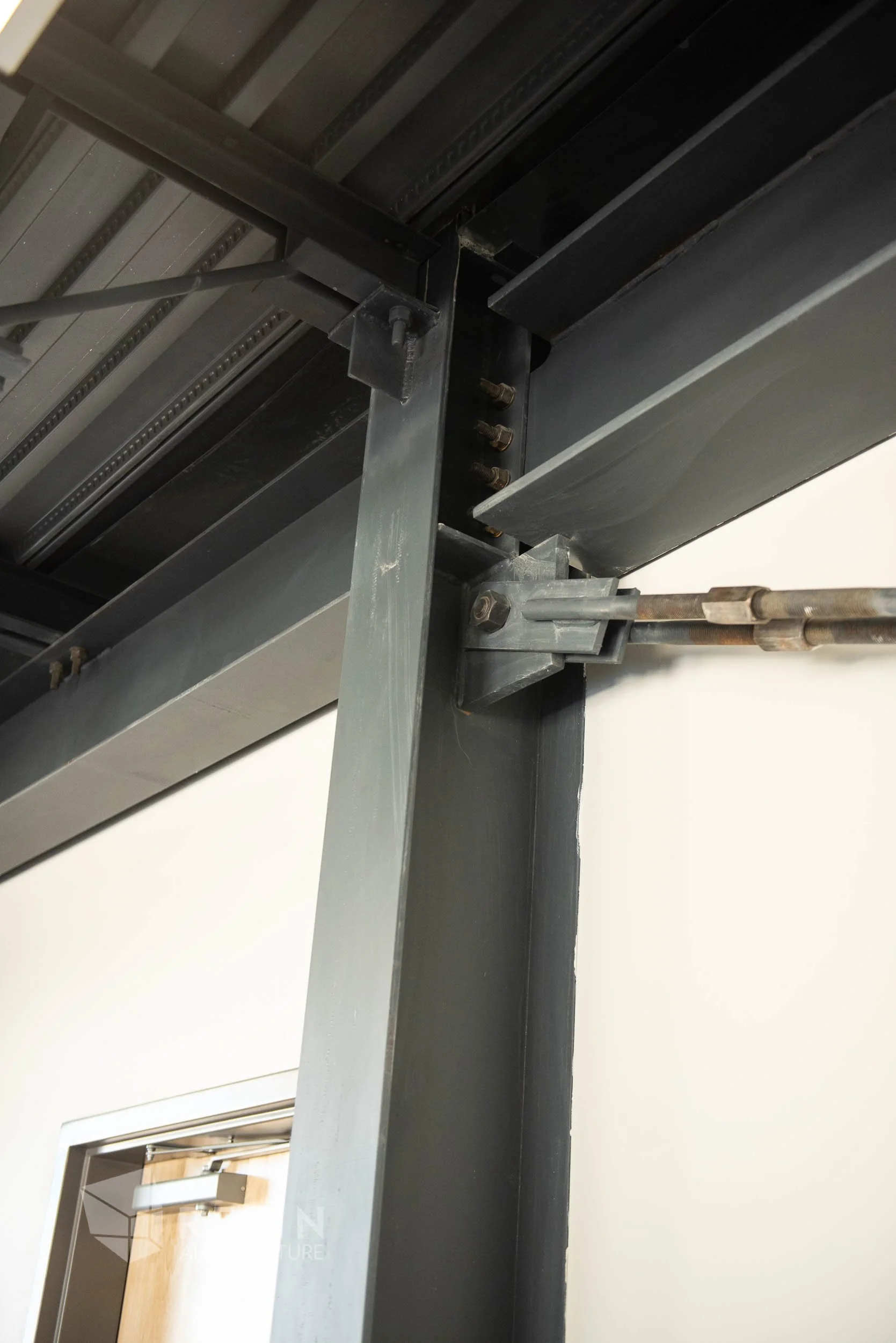 Close-up view of a metal doorway frame under construction, showing steel beams, bolts, and brackets.