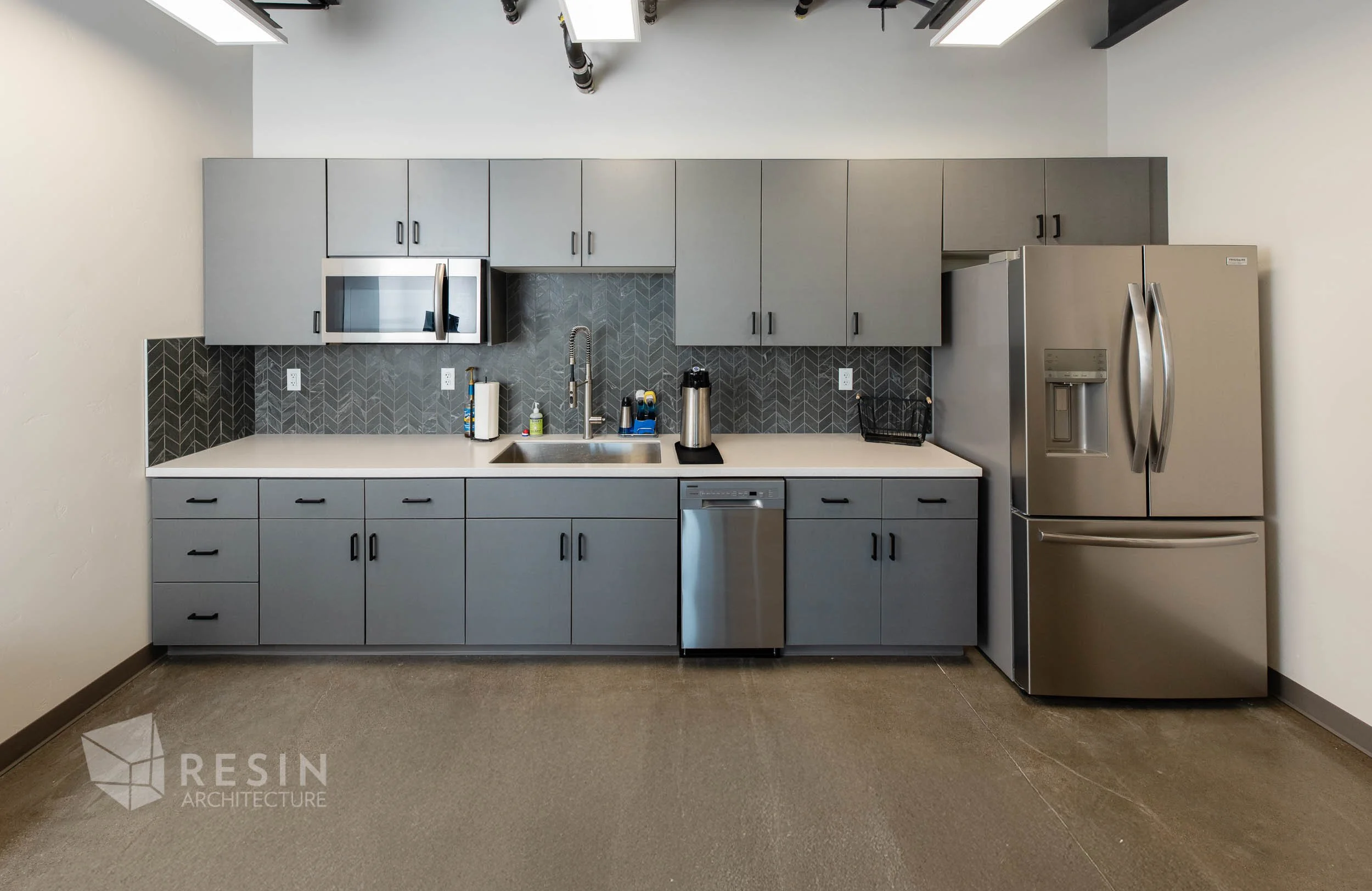 Modern kitchen with gray cabinets, stainless steel appliances, and a patterned gray backsplash.