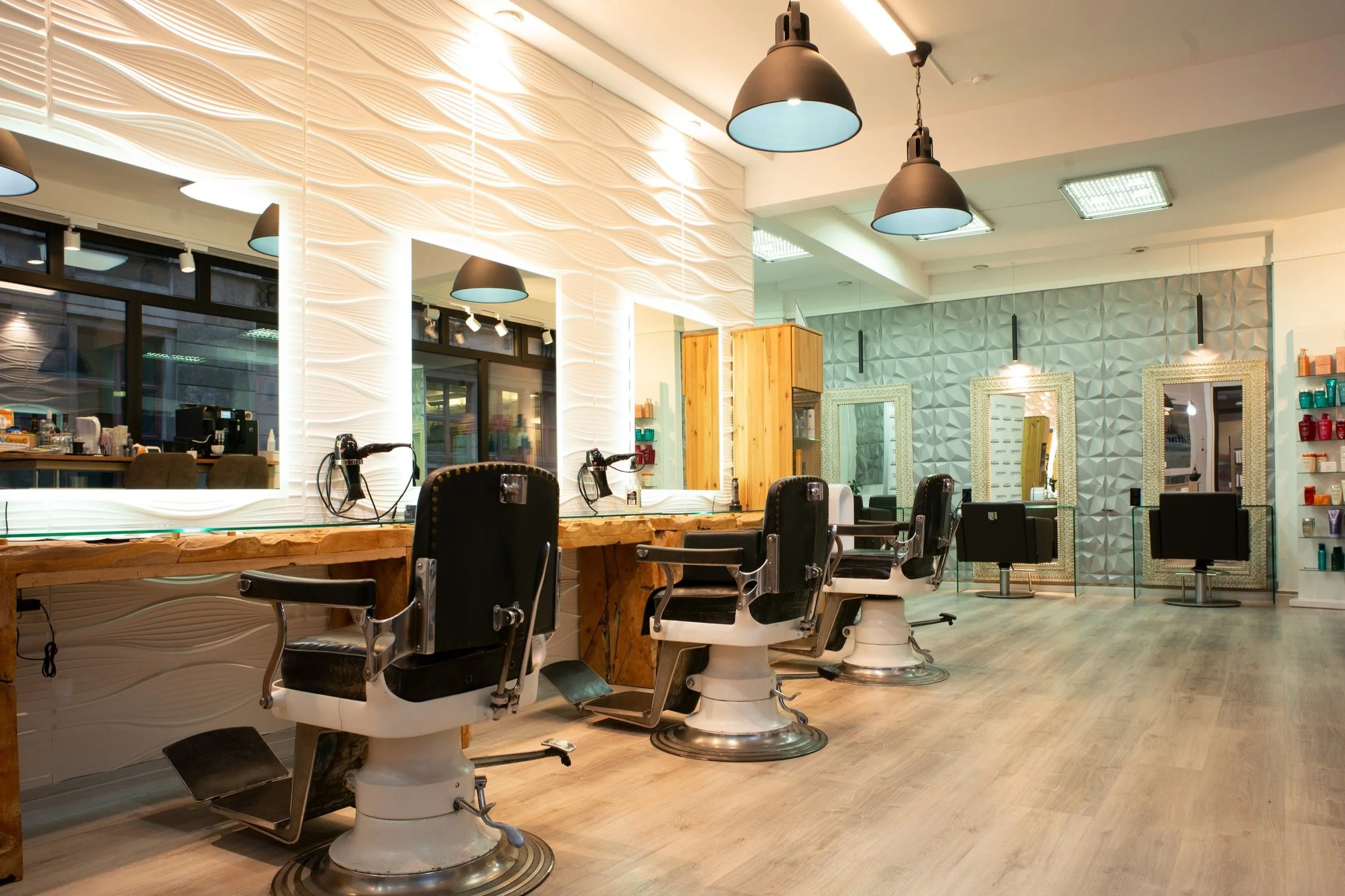 Innenansicht Alsterschnitt Hamburg mit Barberstühlen für Herren und Frisierplätzen mit goldgerahmten Spiegeln für Damen